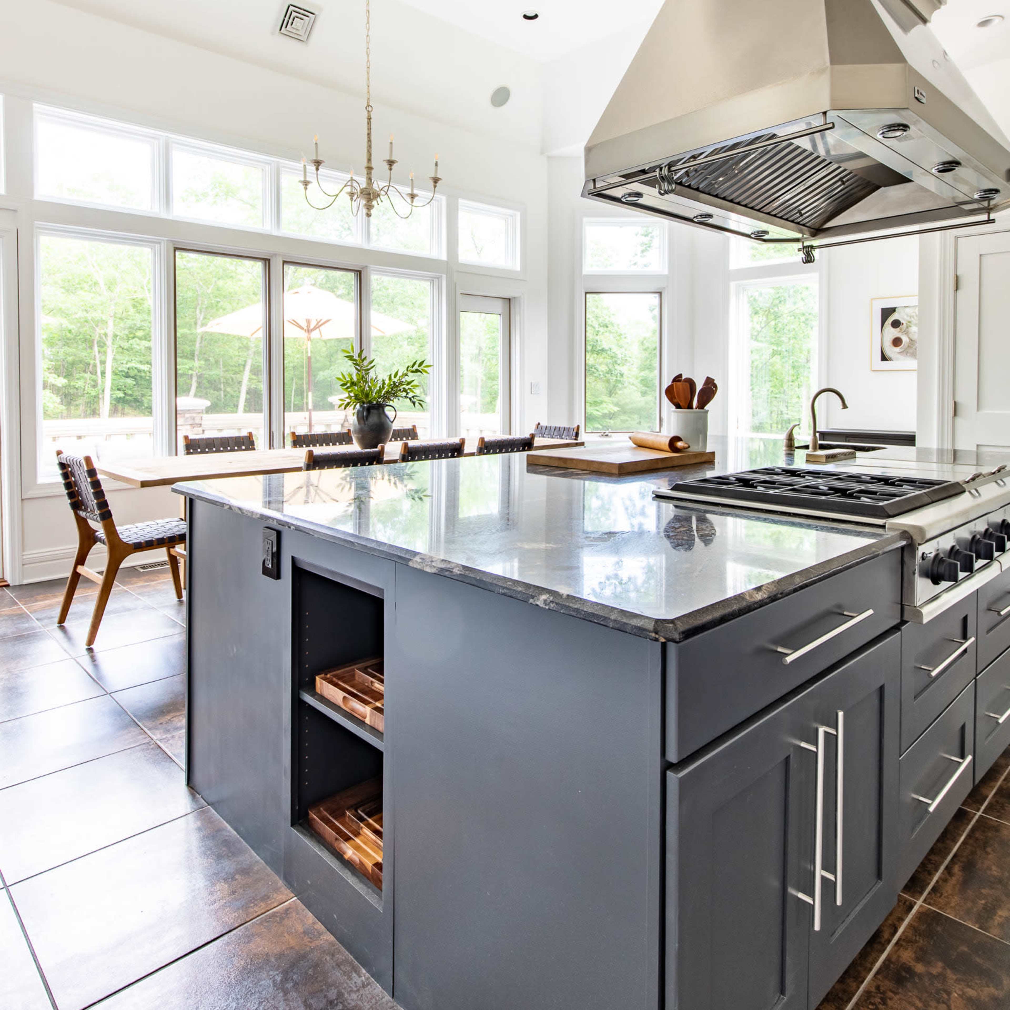 The kitchen features a central island with storage, a stainless steel range hood, and large windows that provide ample natural light.