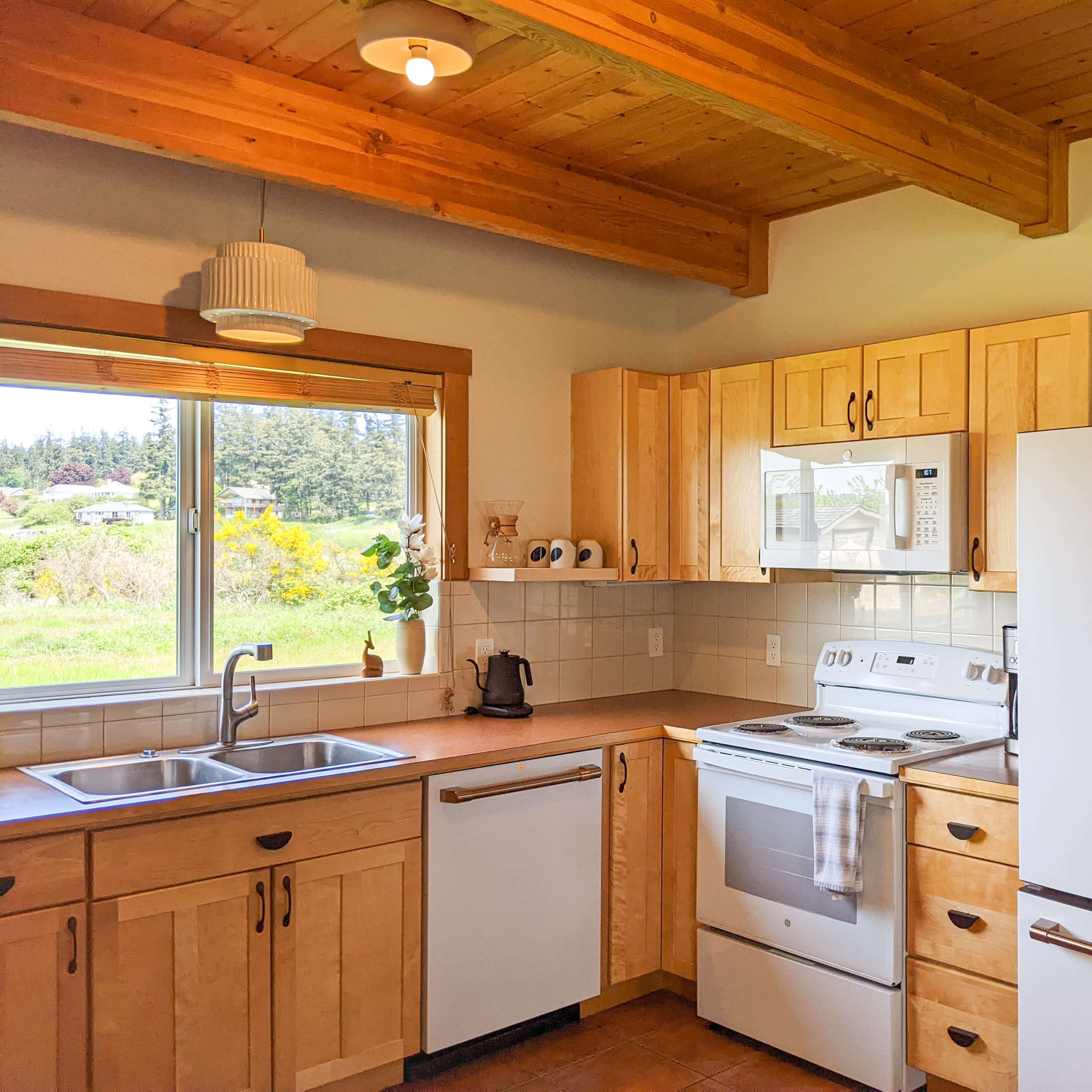 A modern kitchen featuring wooden cabinetry, stainless steel appliances, and a window with a view of the outdoors.