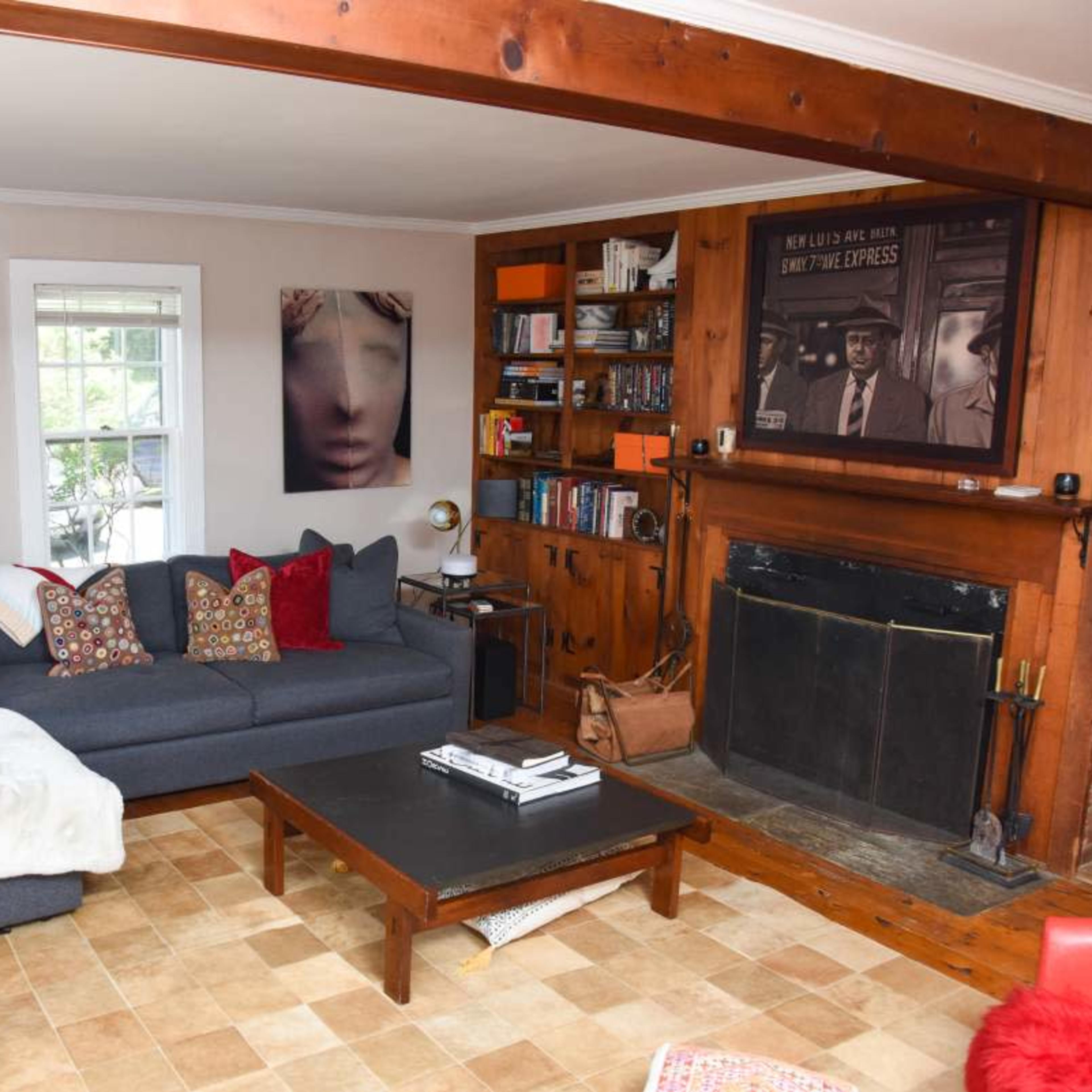 A cozy living room features a sectional sofa adorned with colorful cushions, a coffee table, and a fireplace surrounded by bookshelves.