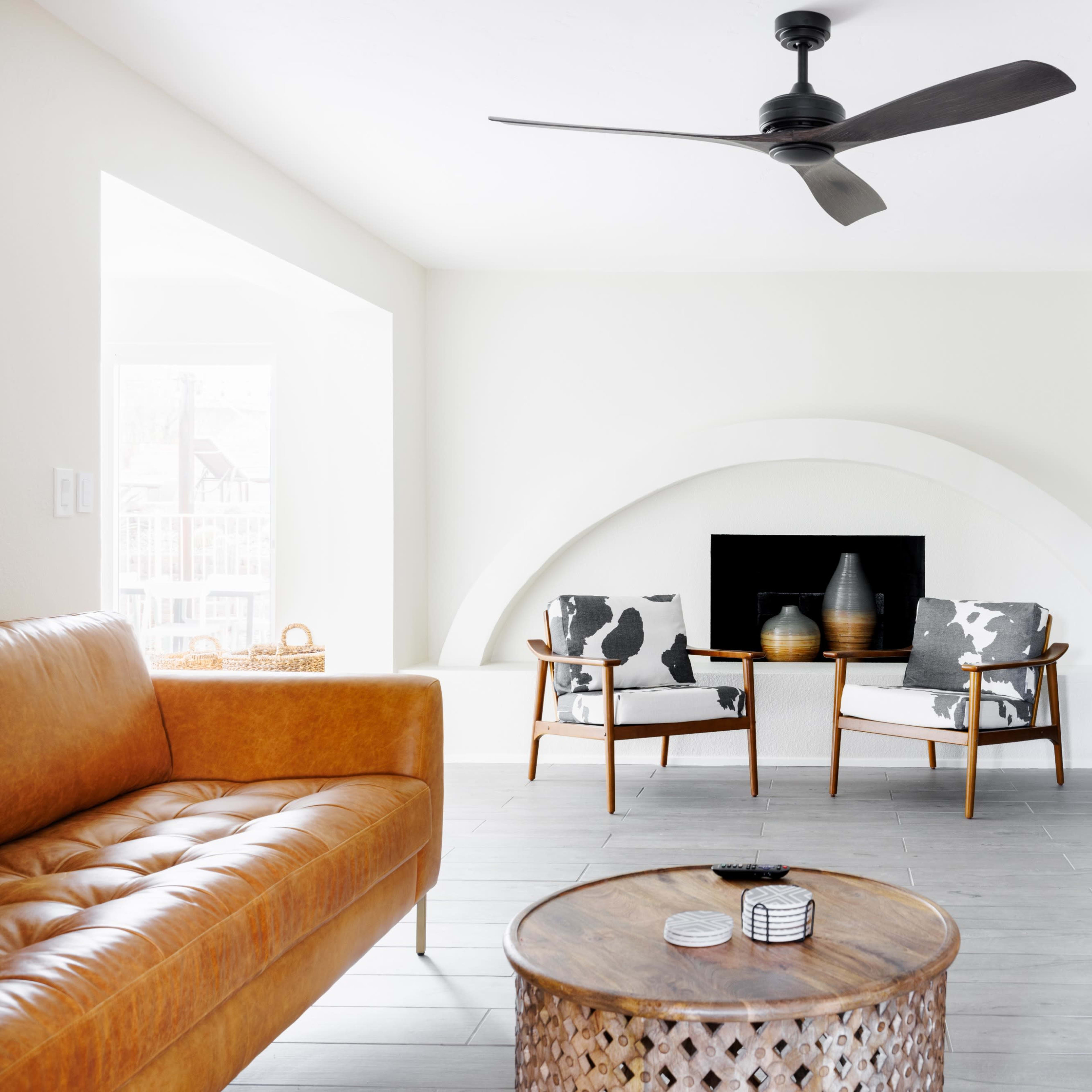 A modern living room featuring two leather sofas, a wooden coffee table, and a fireplace with two chairs positioned nearby.