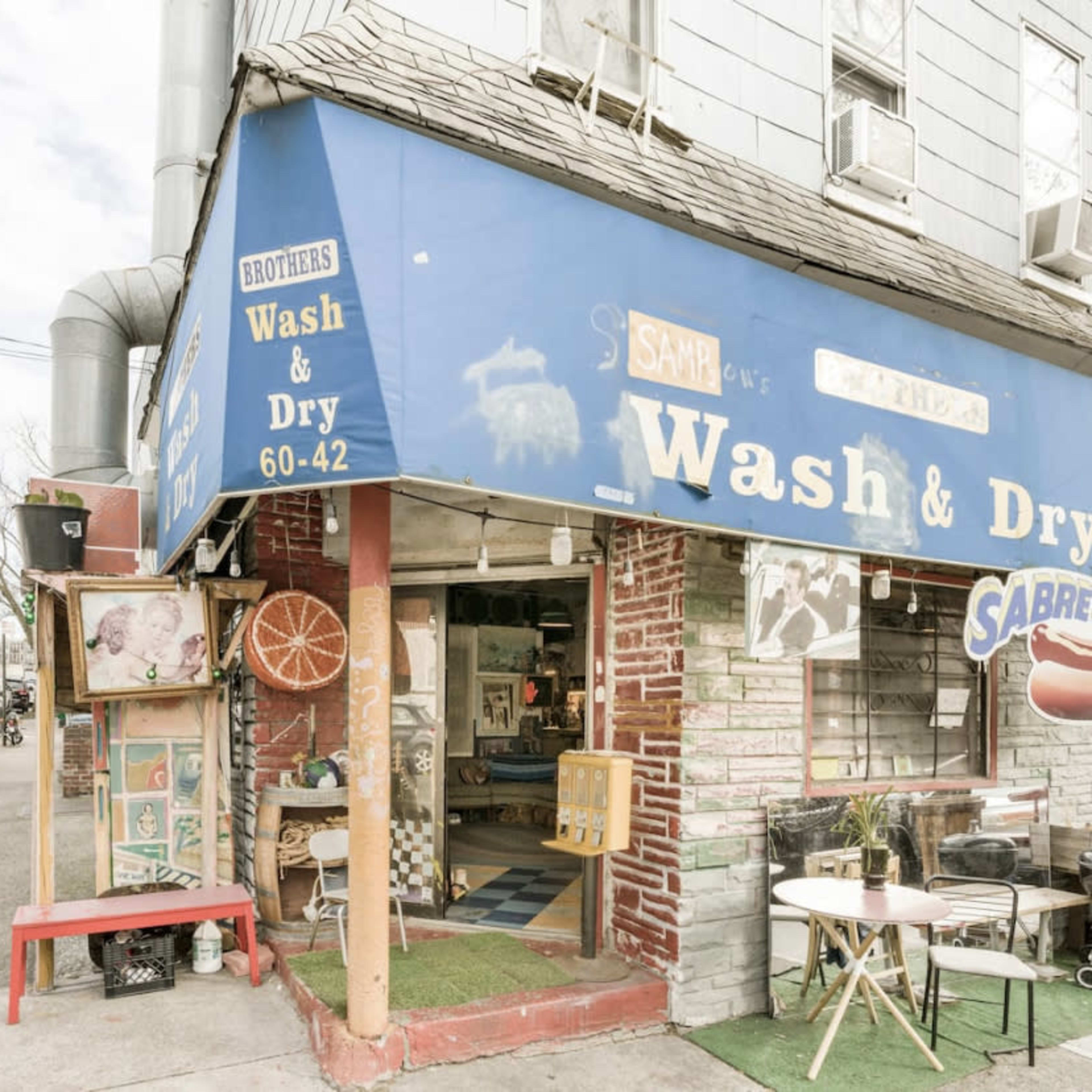 A laundromat called "Brothers Wash & Dry," featuring a blue awning and a colorful storefront with various signs and decor.