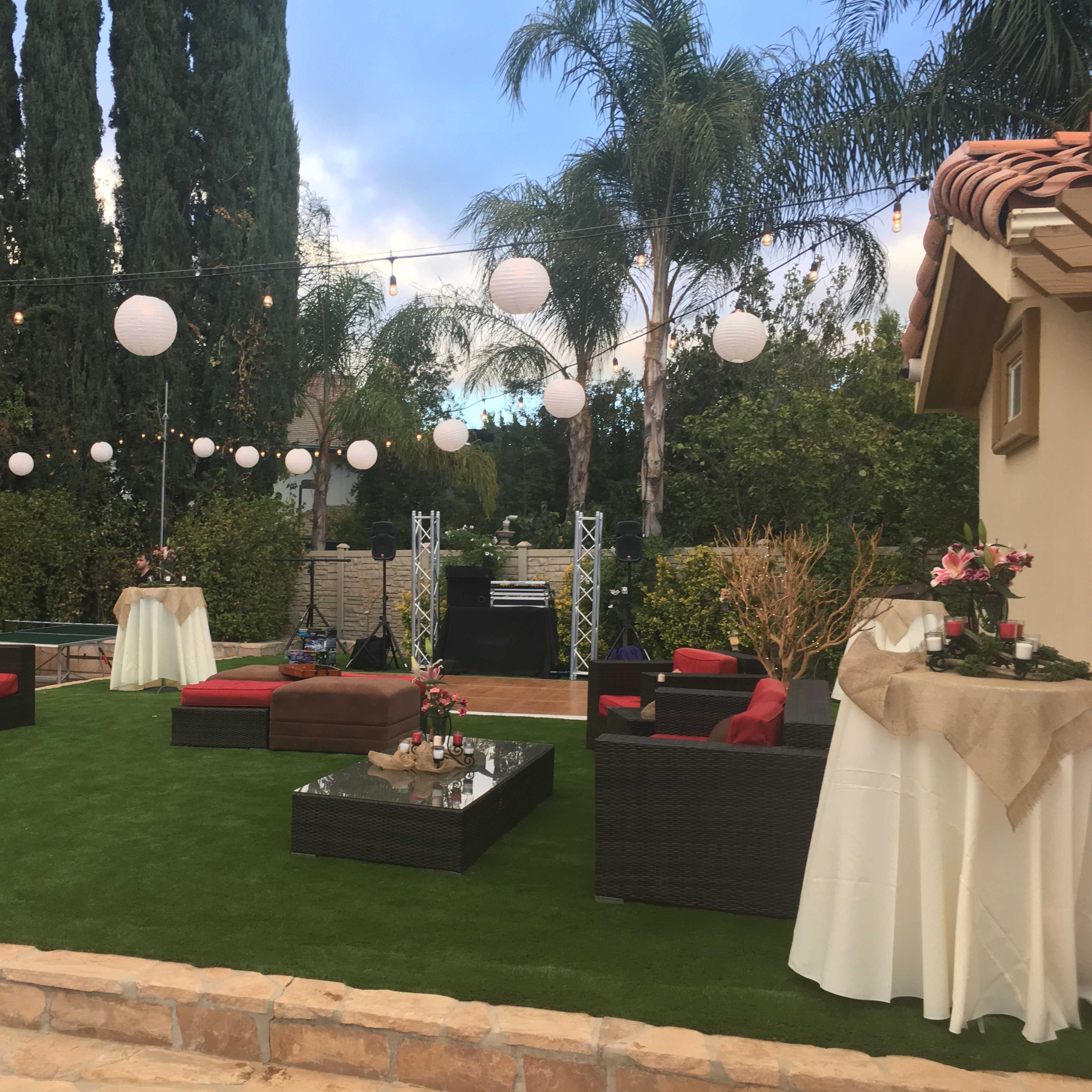 An outdoor event space with seating areas, decorative lights, and greenery.