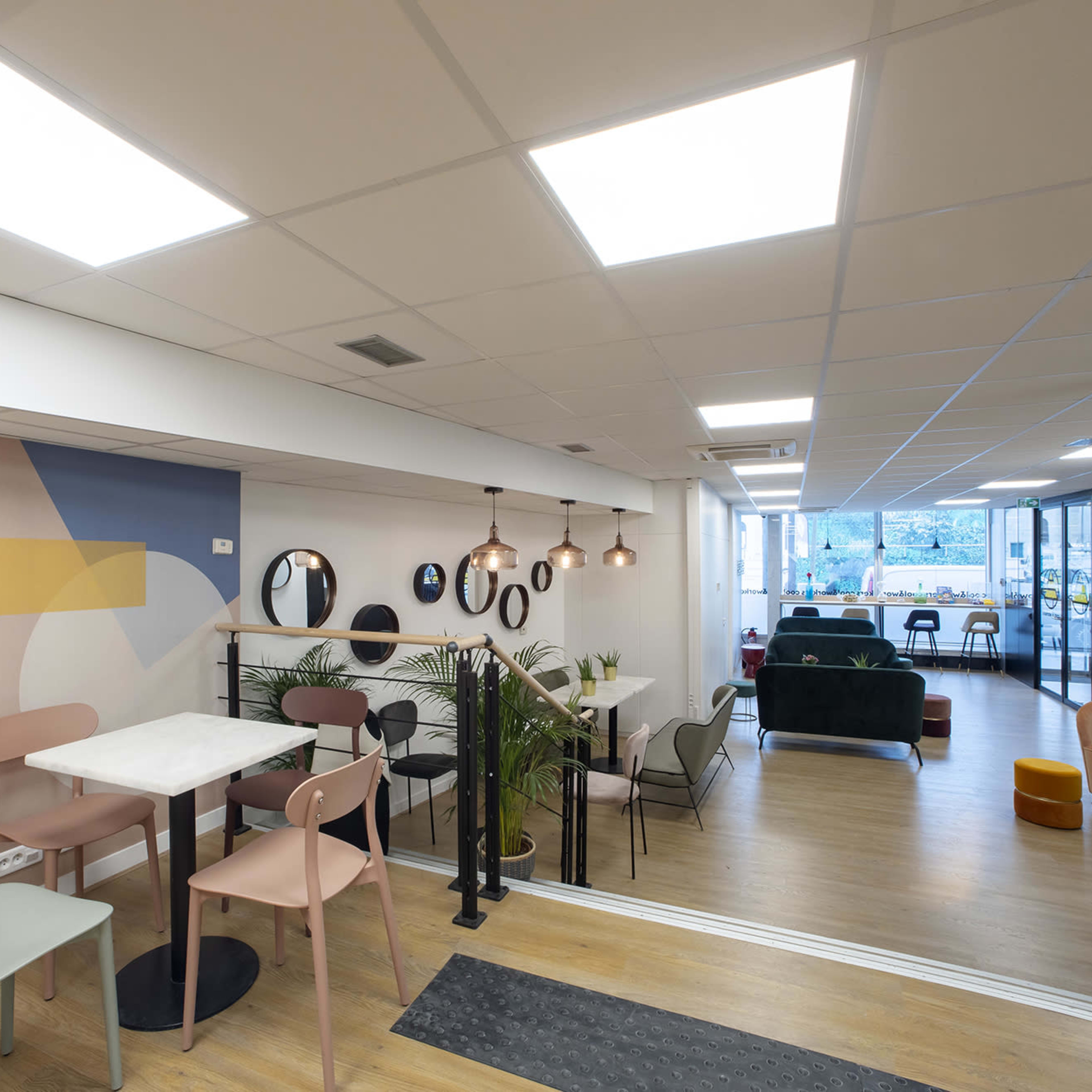 A modern interior space featuring a dining area with stylish tables and chairs, decorative mirrors on the walls, and a lounge area with comfortable seating.