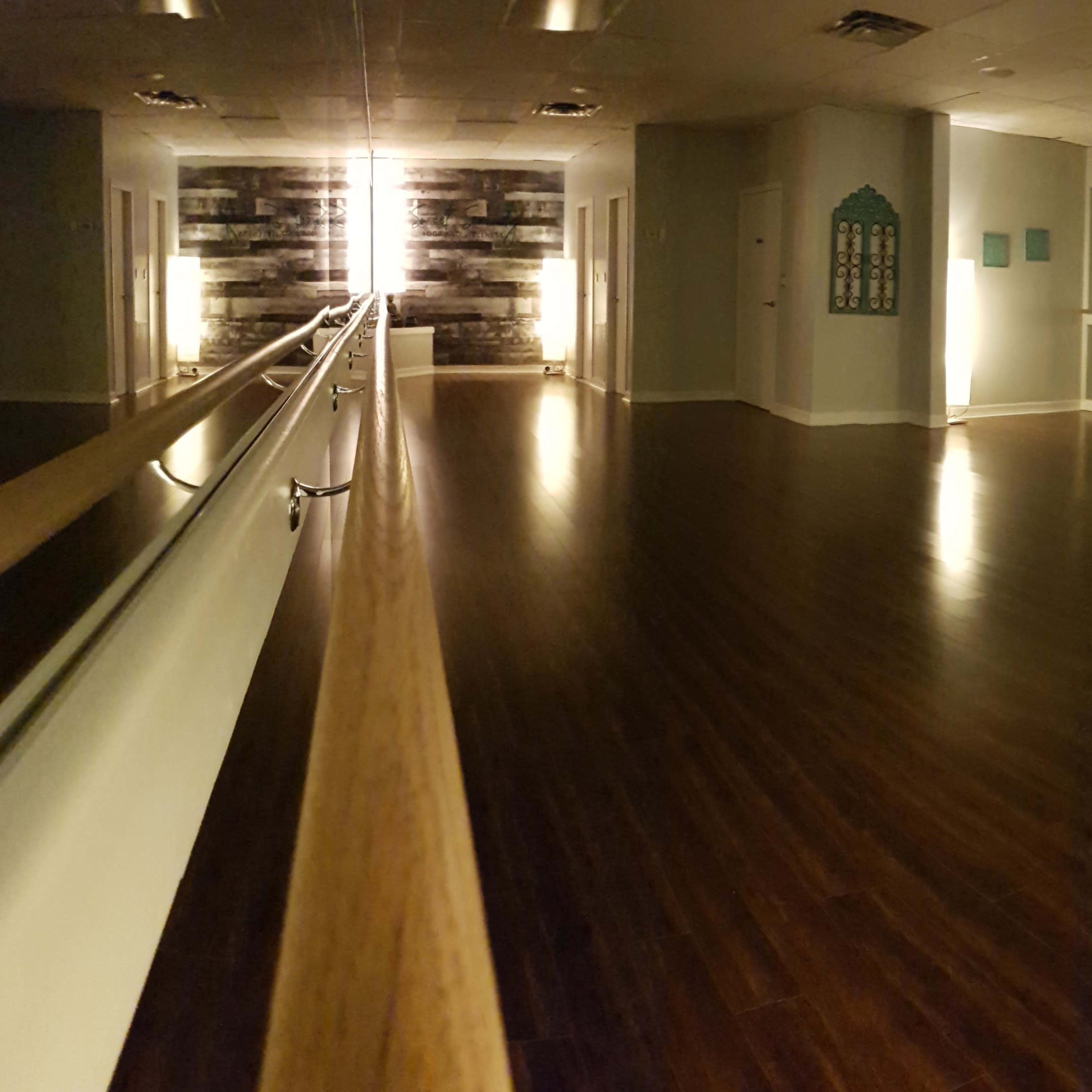 A polished dance studio features a wooden floor, mirrored walls, and ambient lighting.