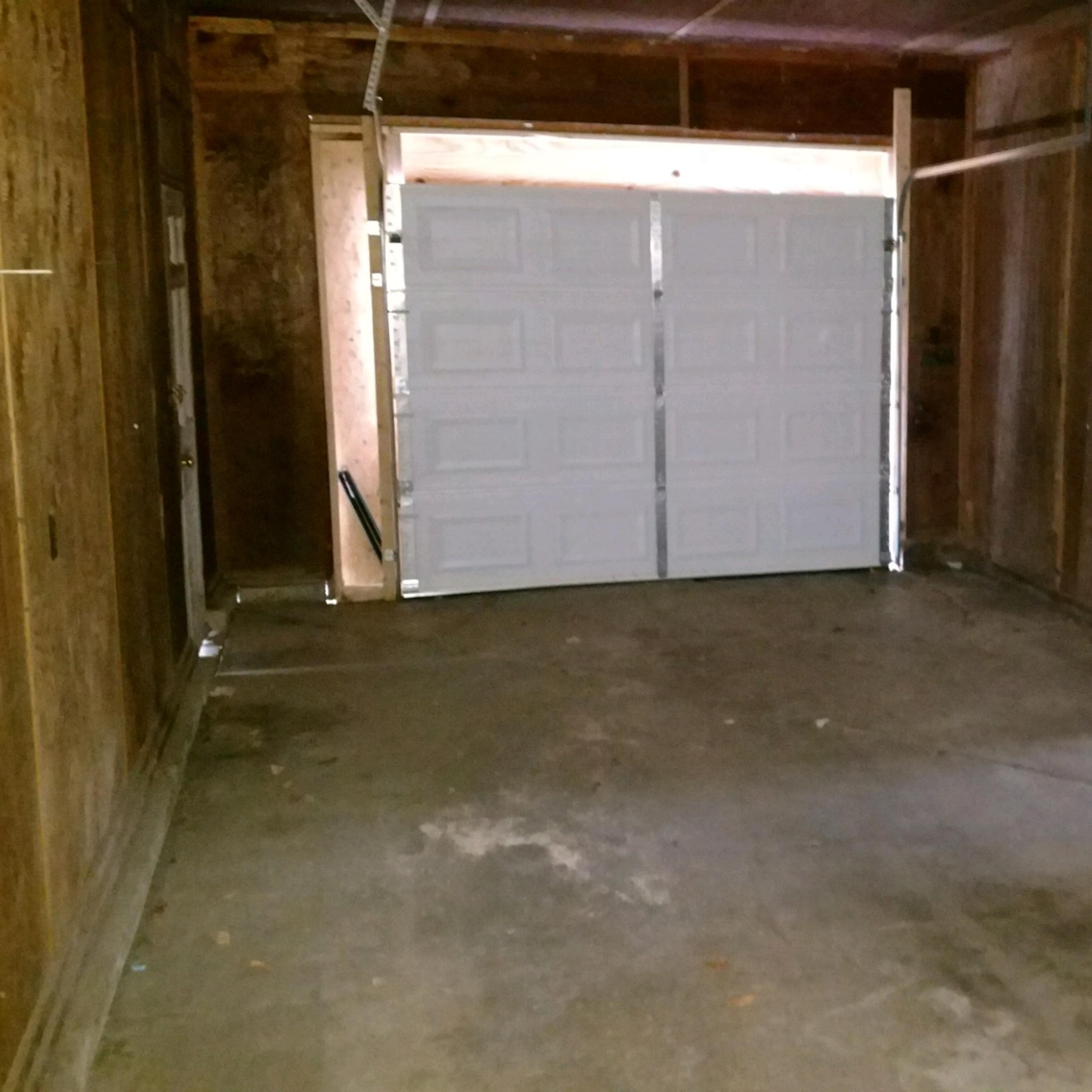 A spacious, empty garage with wooden walls and a double door at the front.