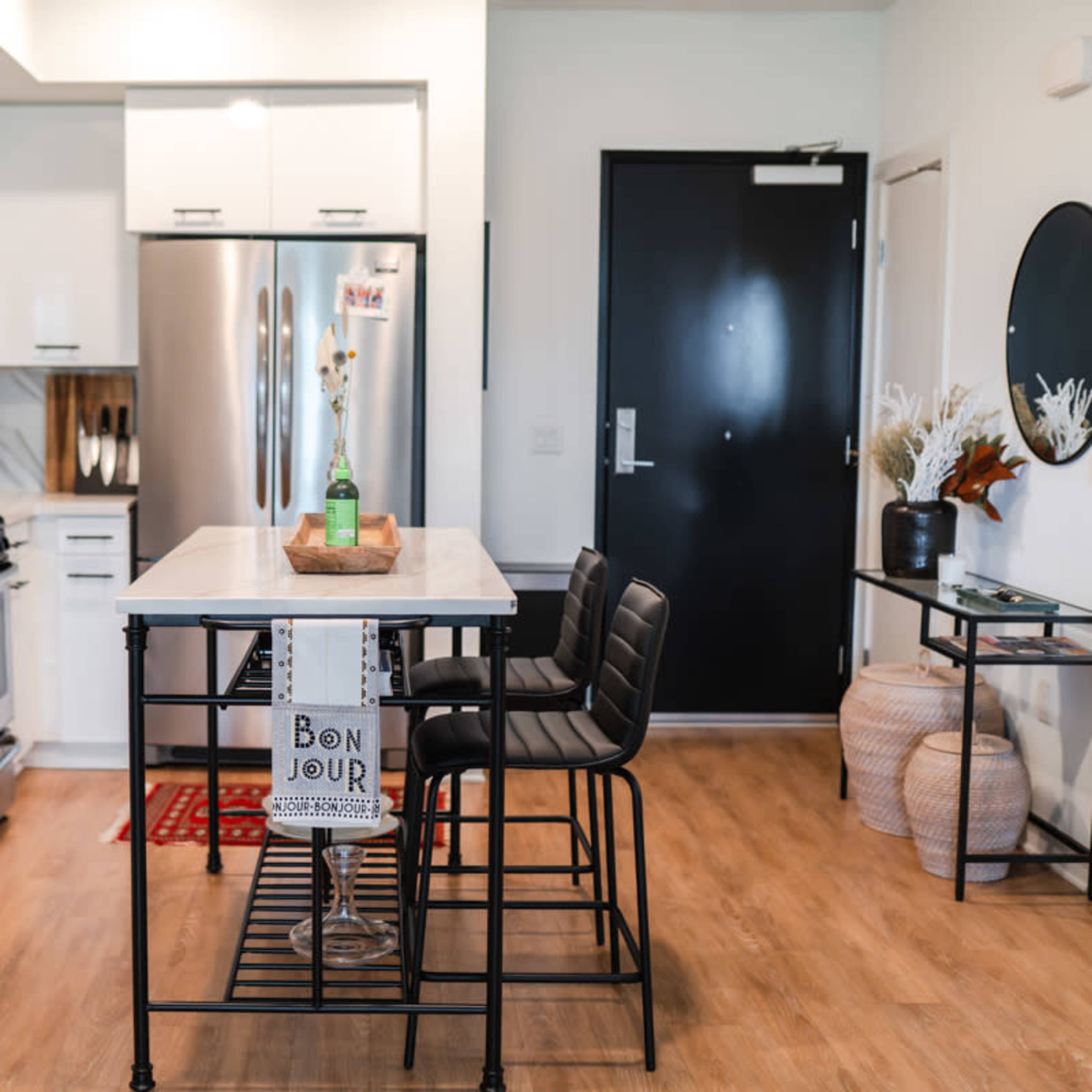 A modern kitchen features sleek white cabinets, stainless steel appliances, and a central island with bar stools.