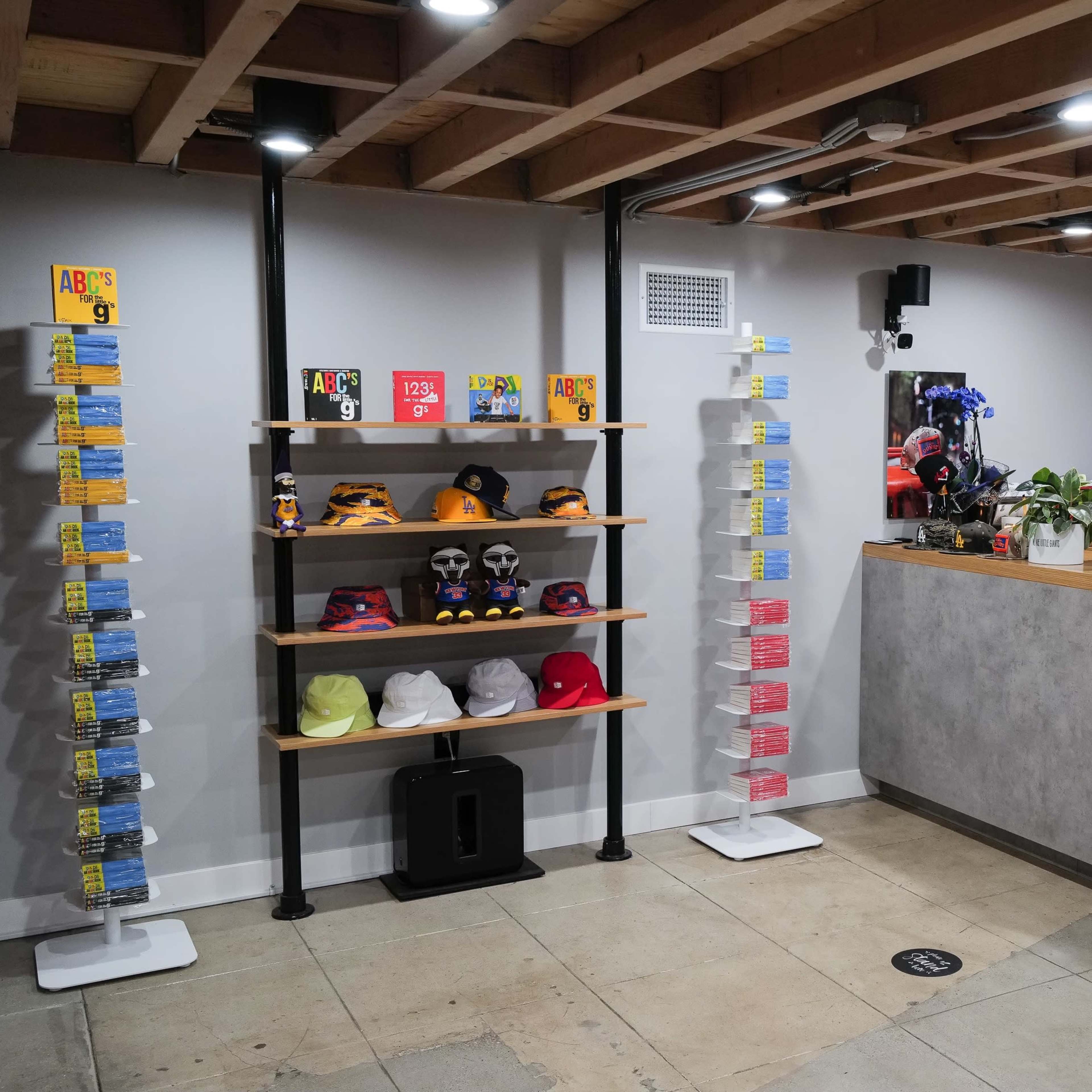 A retail space with shelves displaying various hats and brochures, alongside a modern reception desk equipped with a computer and plants.