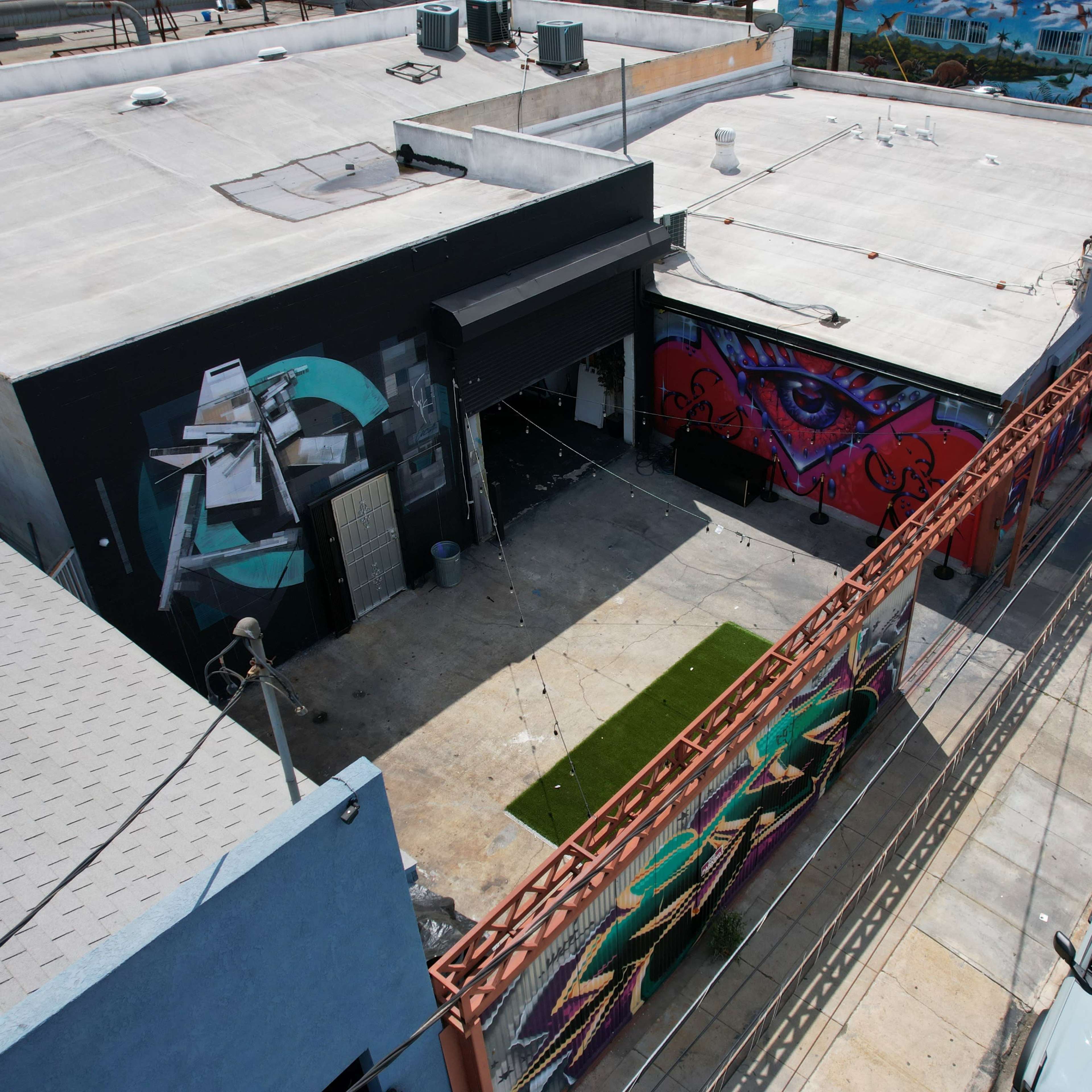 An overhead view of a commercial building with colorful murals on its exterior and an open courtyard area.