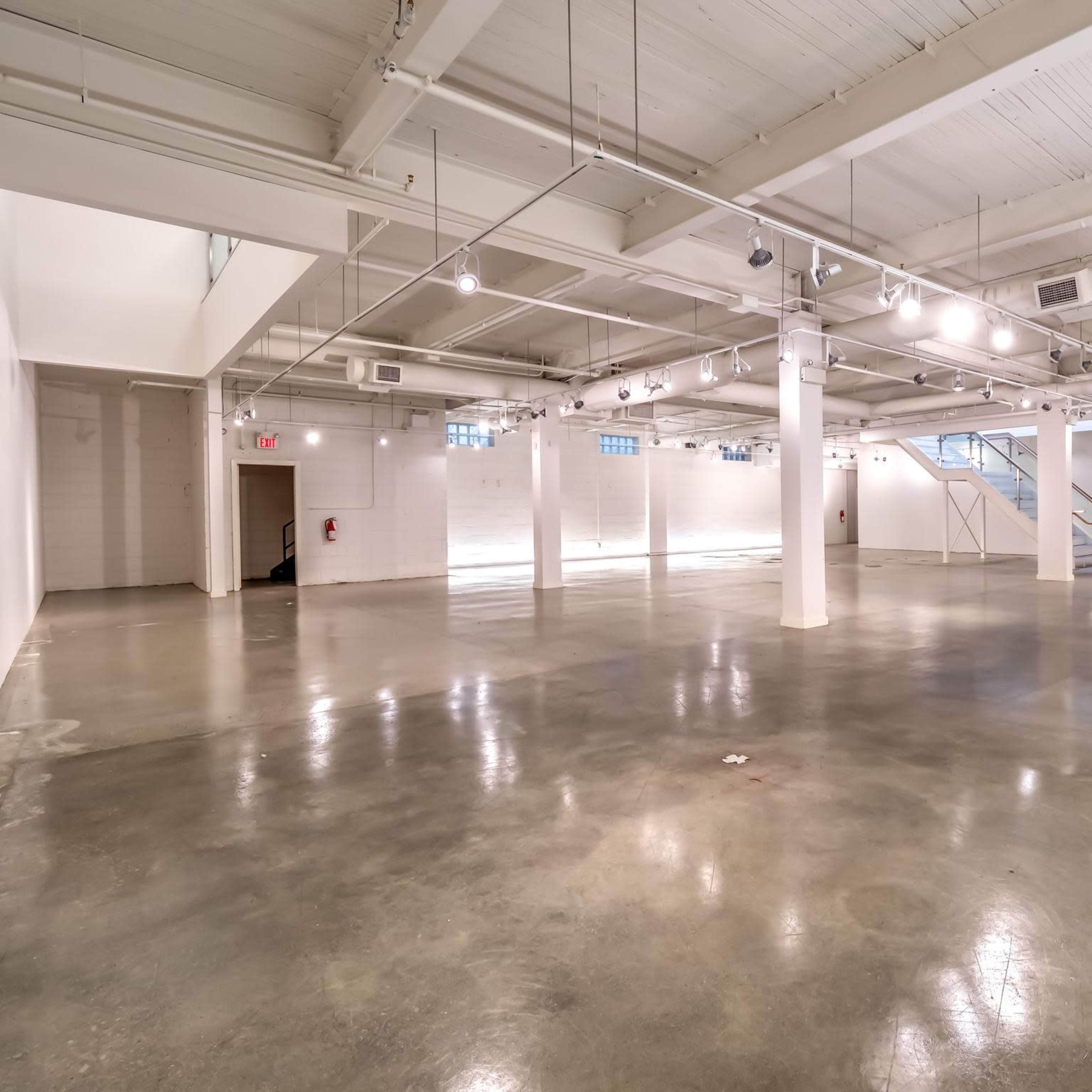 A spacious, empty indoor area with polished concrete floors and ample overhead lighting.