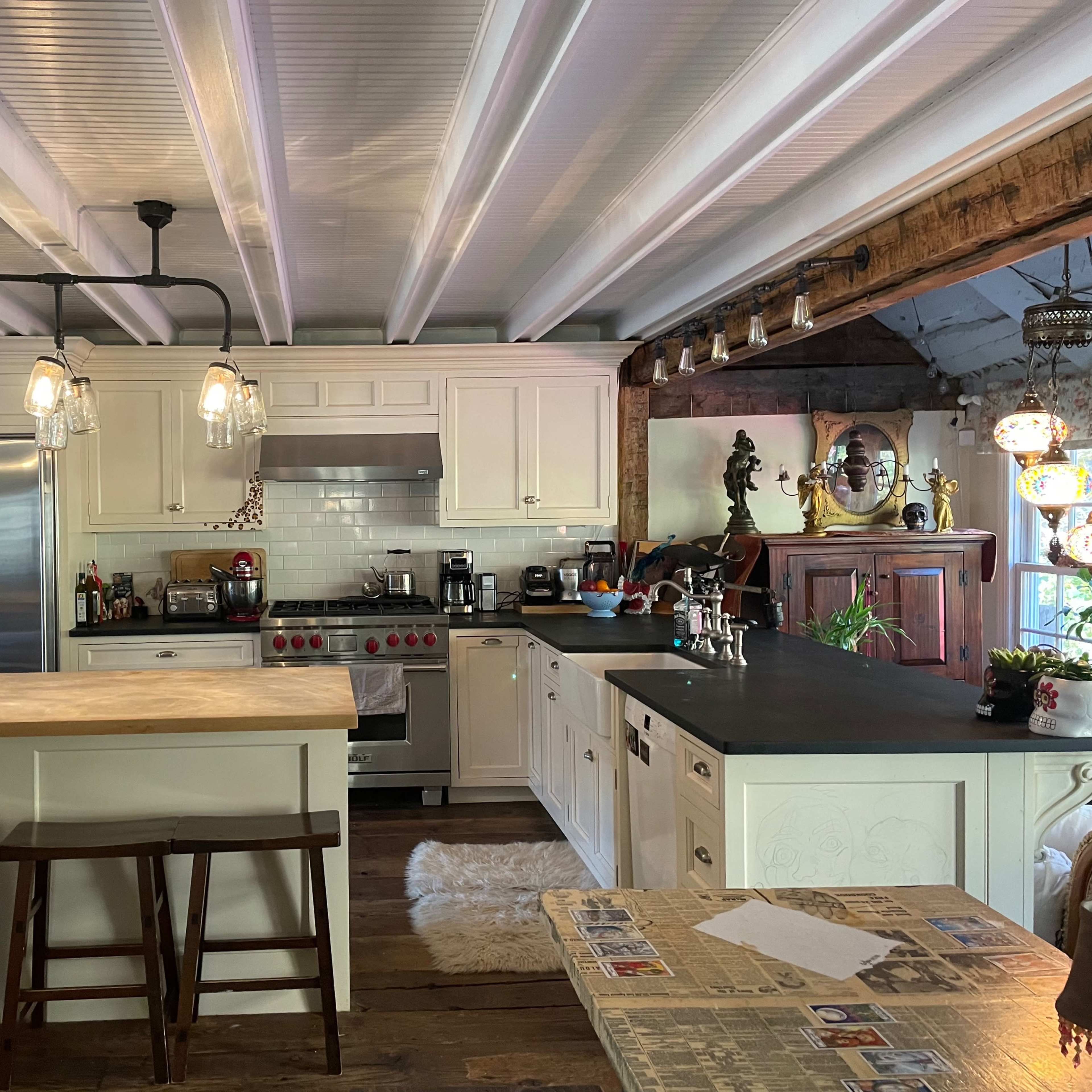 The kitchen features white cabinetry, a stainless steel refrigerator, and a central island with wooden countertops and bar stools.