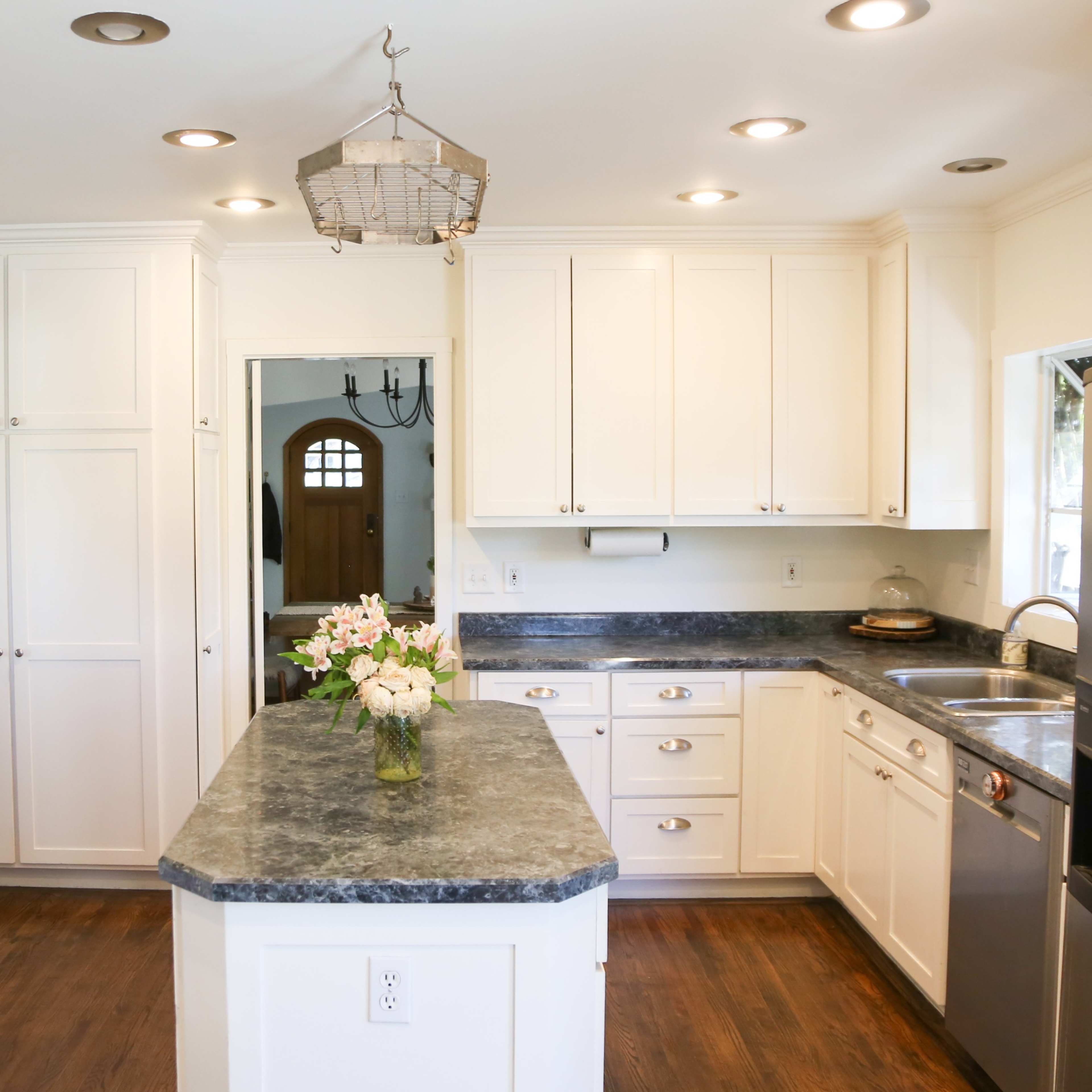 The kitchen features white cabinetry, a center island, stainless steel appliances, and dark countertops.