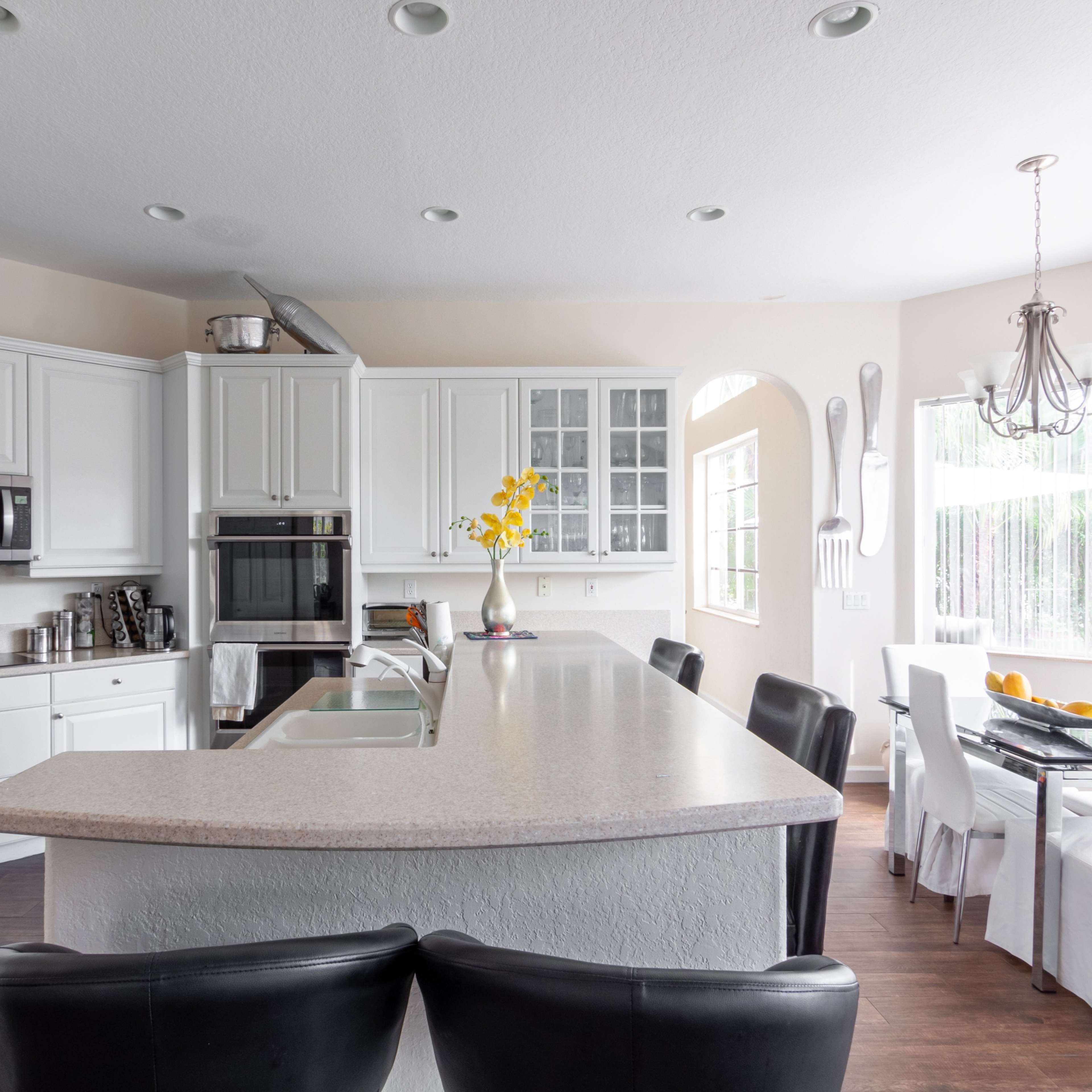 A modern kitchen with white cabinetry, stainless steel appliances, and a dining area featuring a table set for meals.