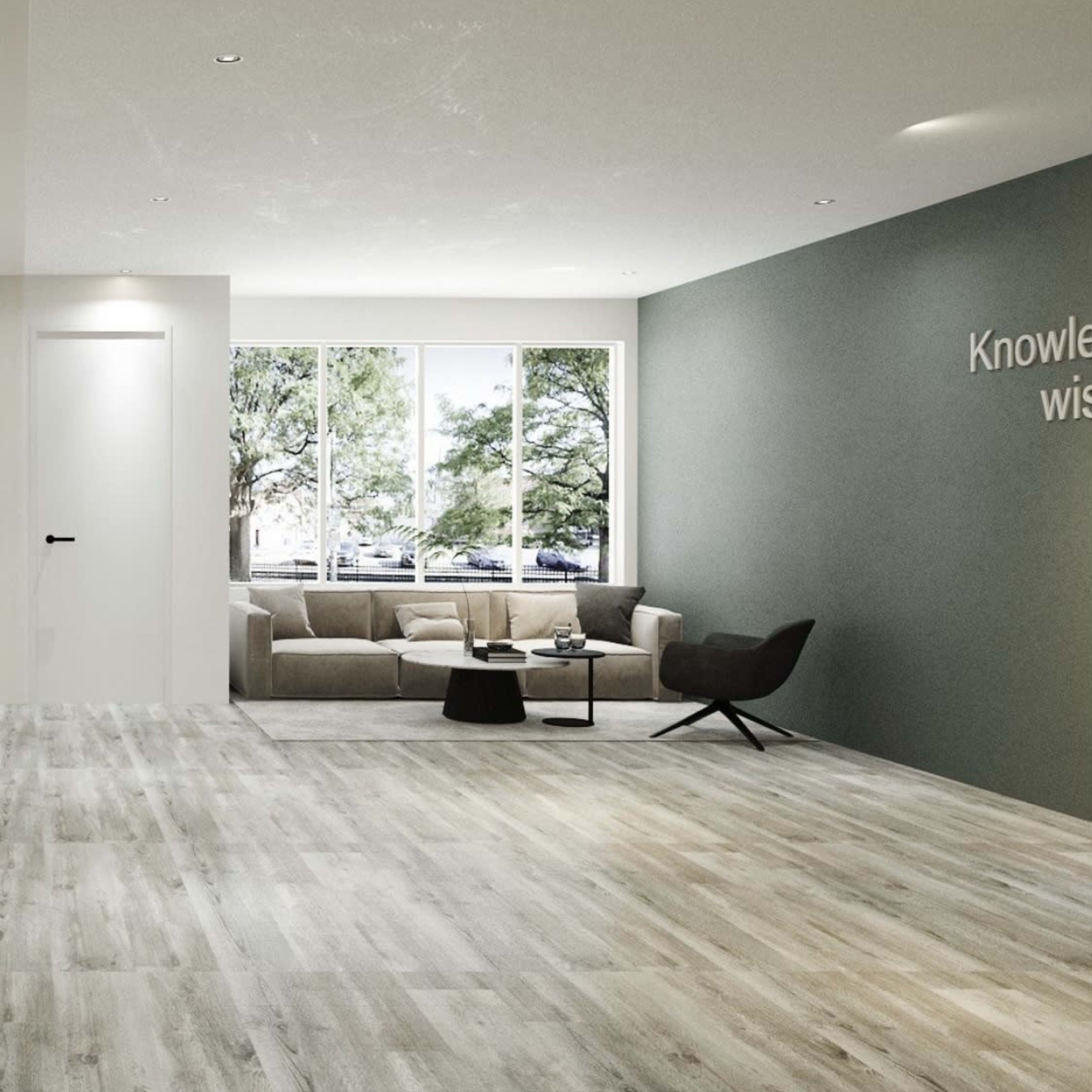 A spacious, modern room features a comfortable seating area with a couch and coffee table, large windows allowing natural light, and a wall with a motivational quote.