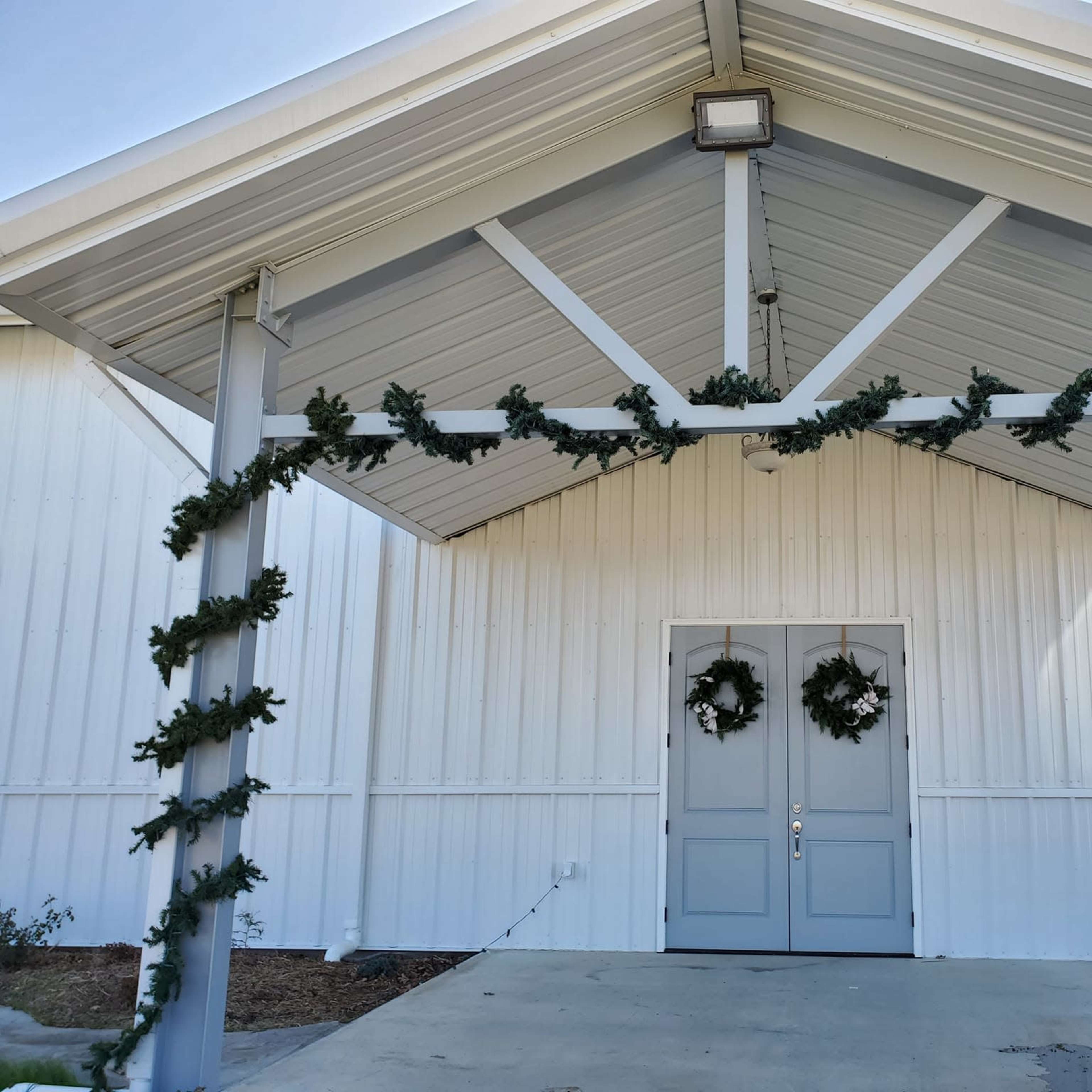 The entrance features a covered awning adorned with garlands and wreaths on either side of the double doors.
