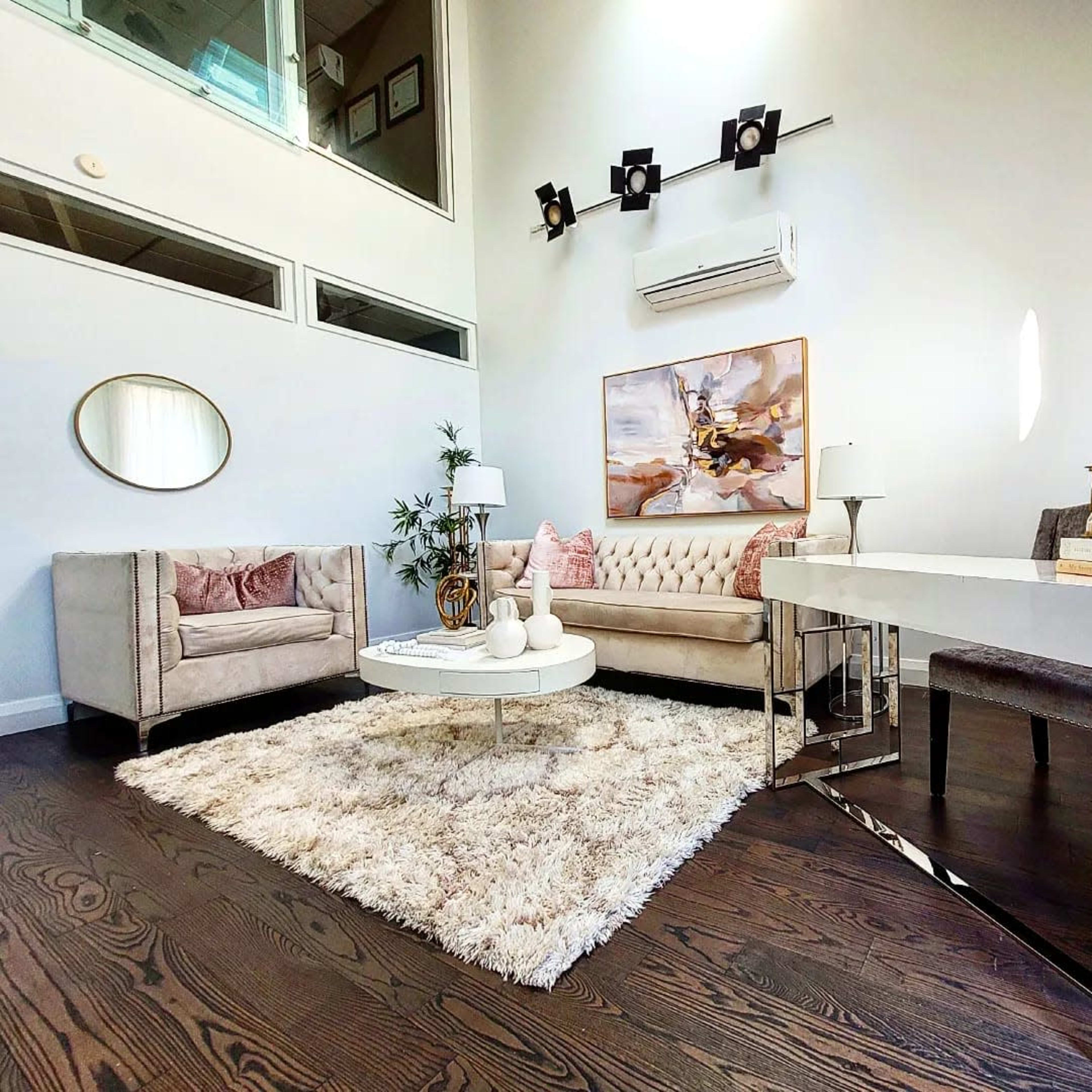 A modern living room with a beige sofa, a round coffee table on a fluffy rug, and a small white console table.