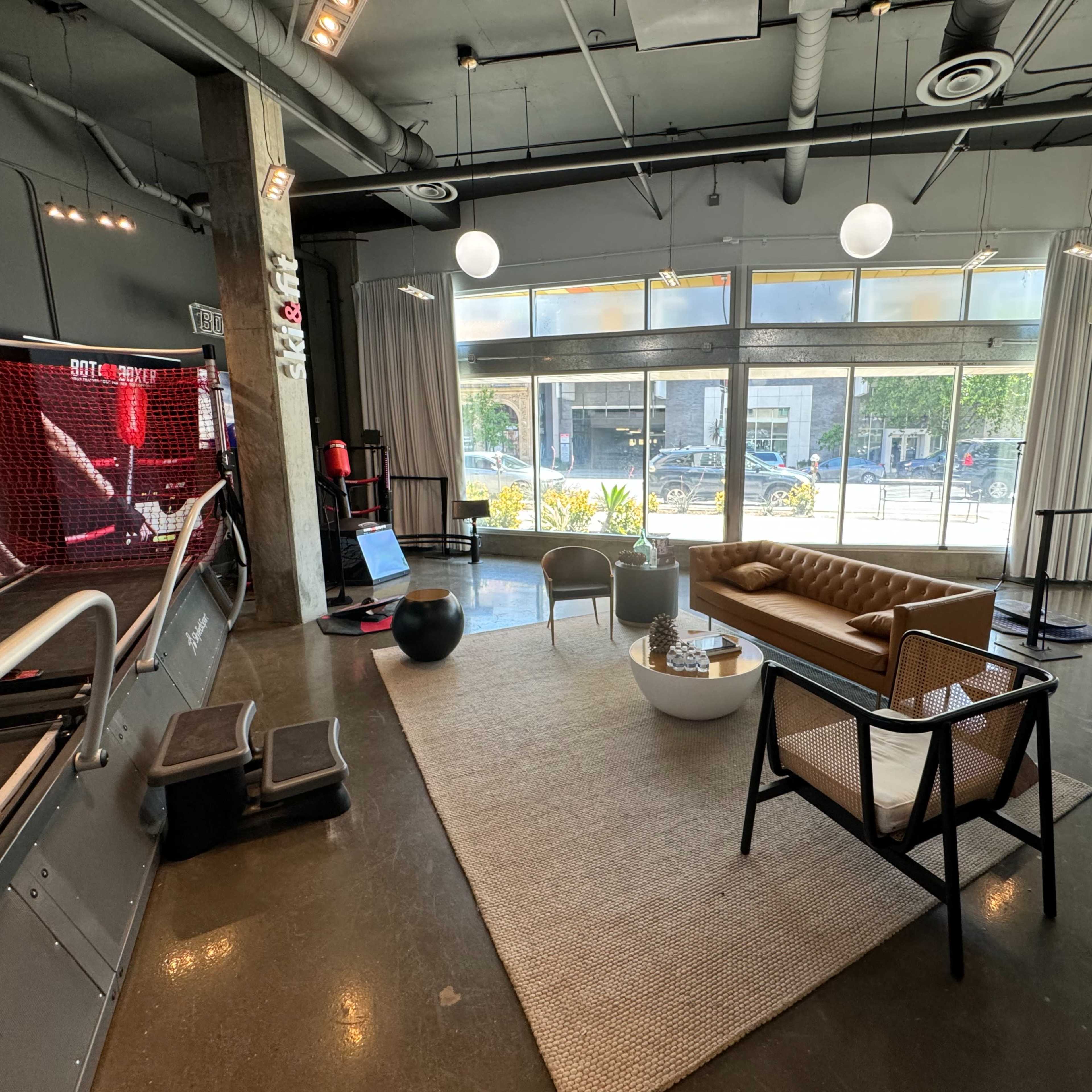 A modern lounge area with a leather sofa, chairs, and large windows allowing natural light to fill the space.