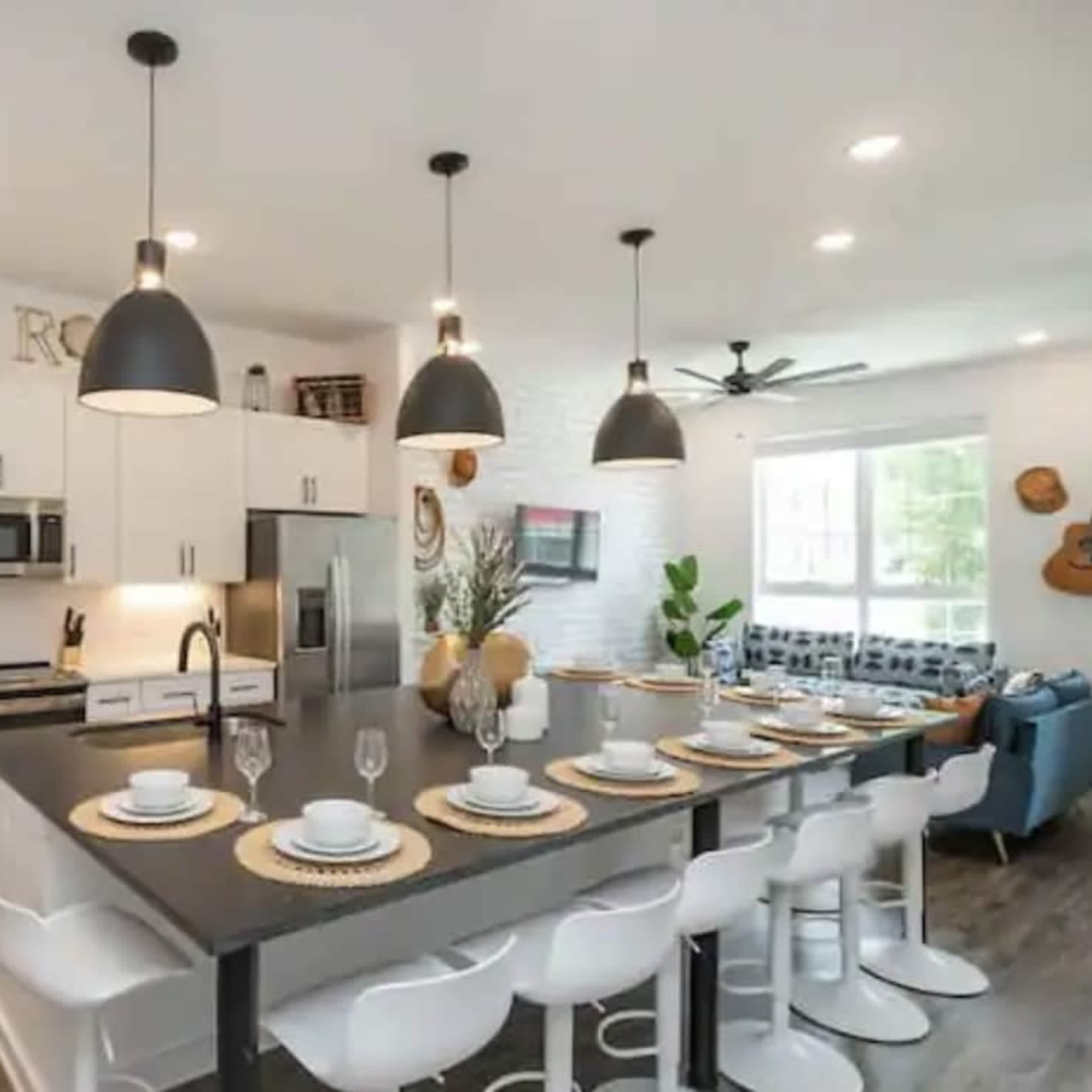 A modern kitchen features white cabinetry, stainless steel appliances, and a large island with seating for eight.