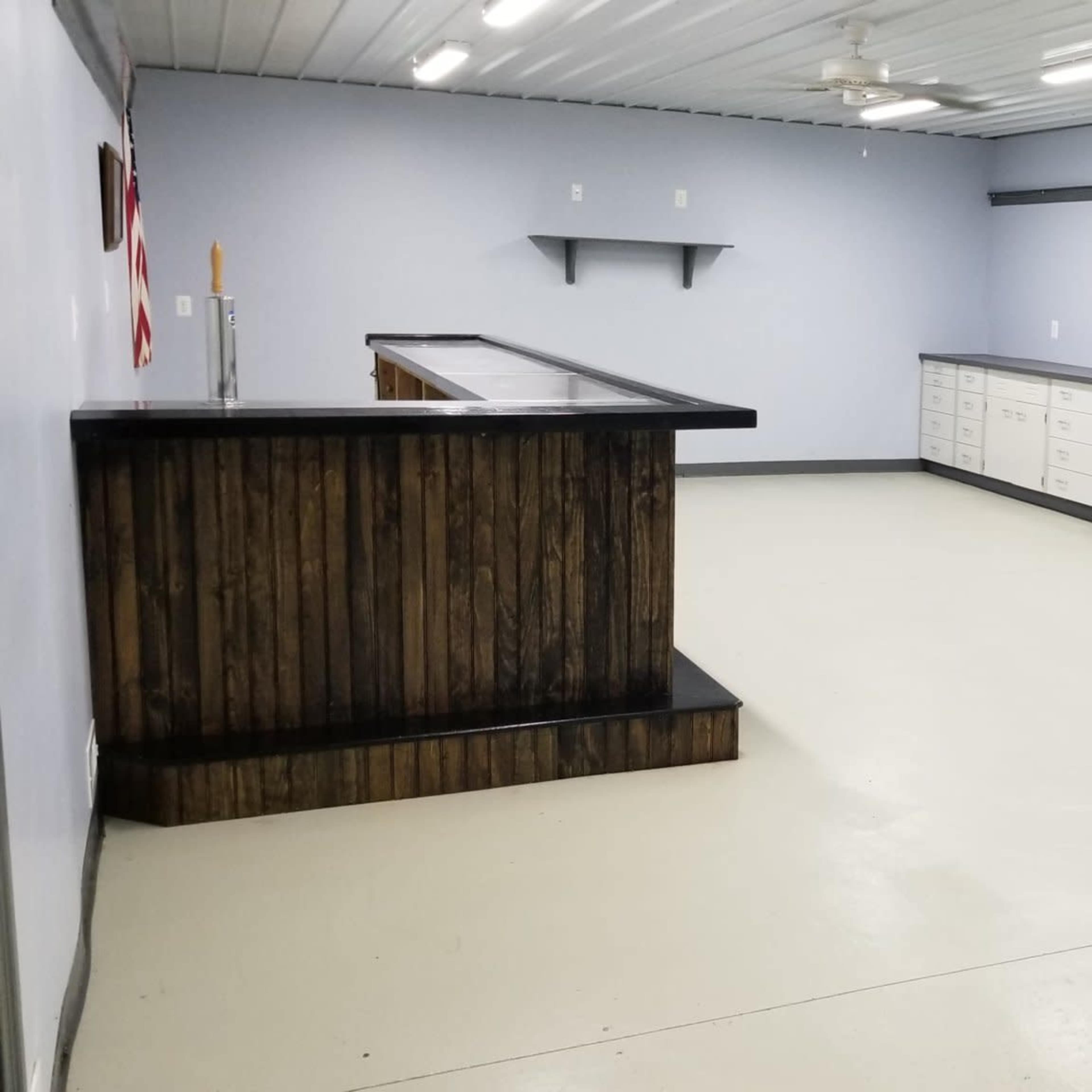 An empty room with light gray walls, a wooden bar counter, and cabinets along one side.