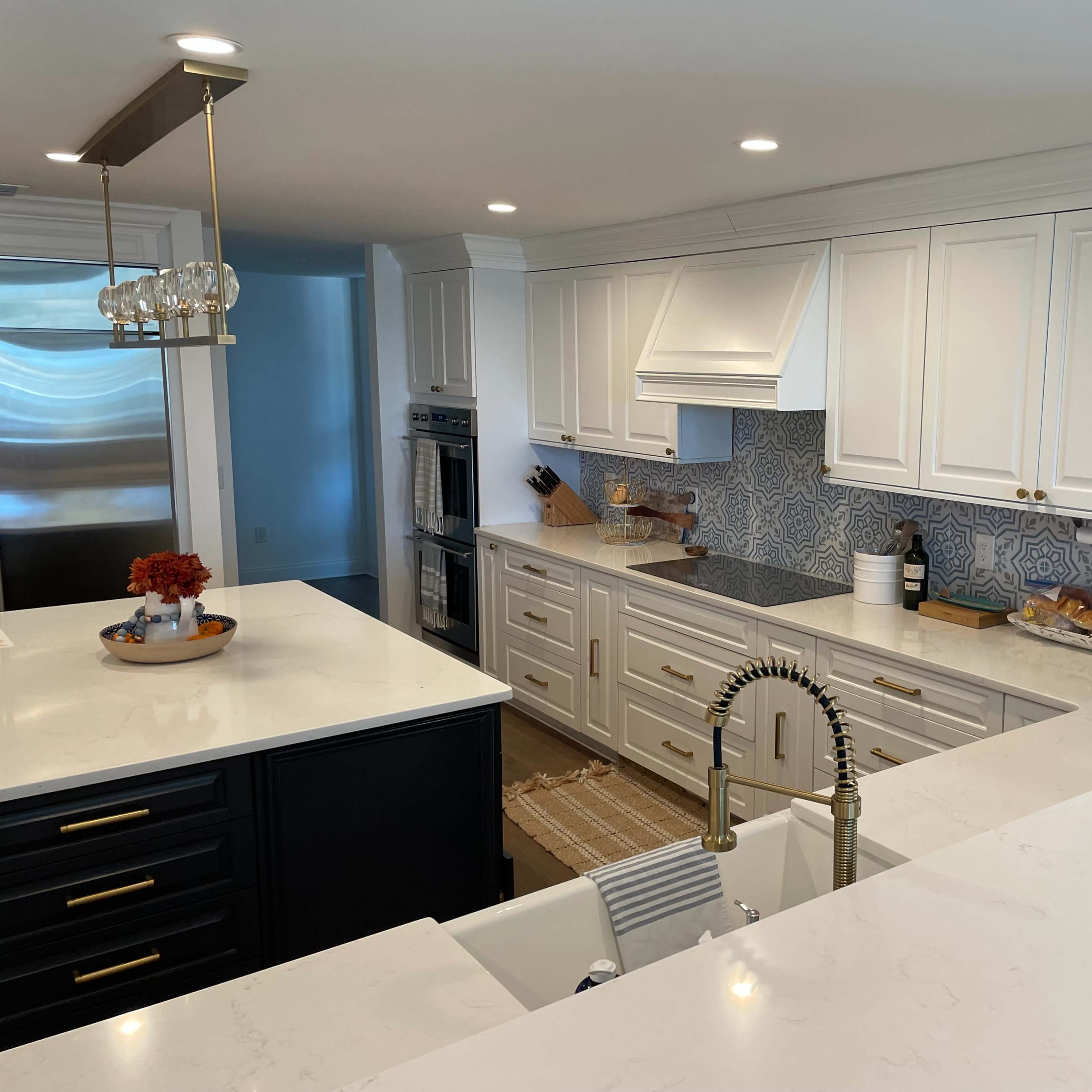 A modern kitchen features white cabinetry, a patterned blue backsplash, and a central island with a black base and a sink.