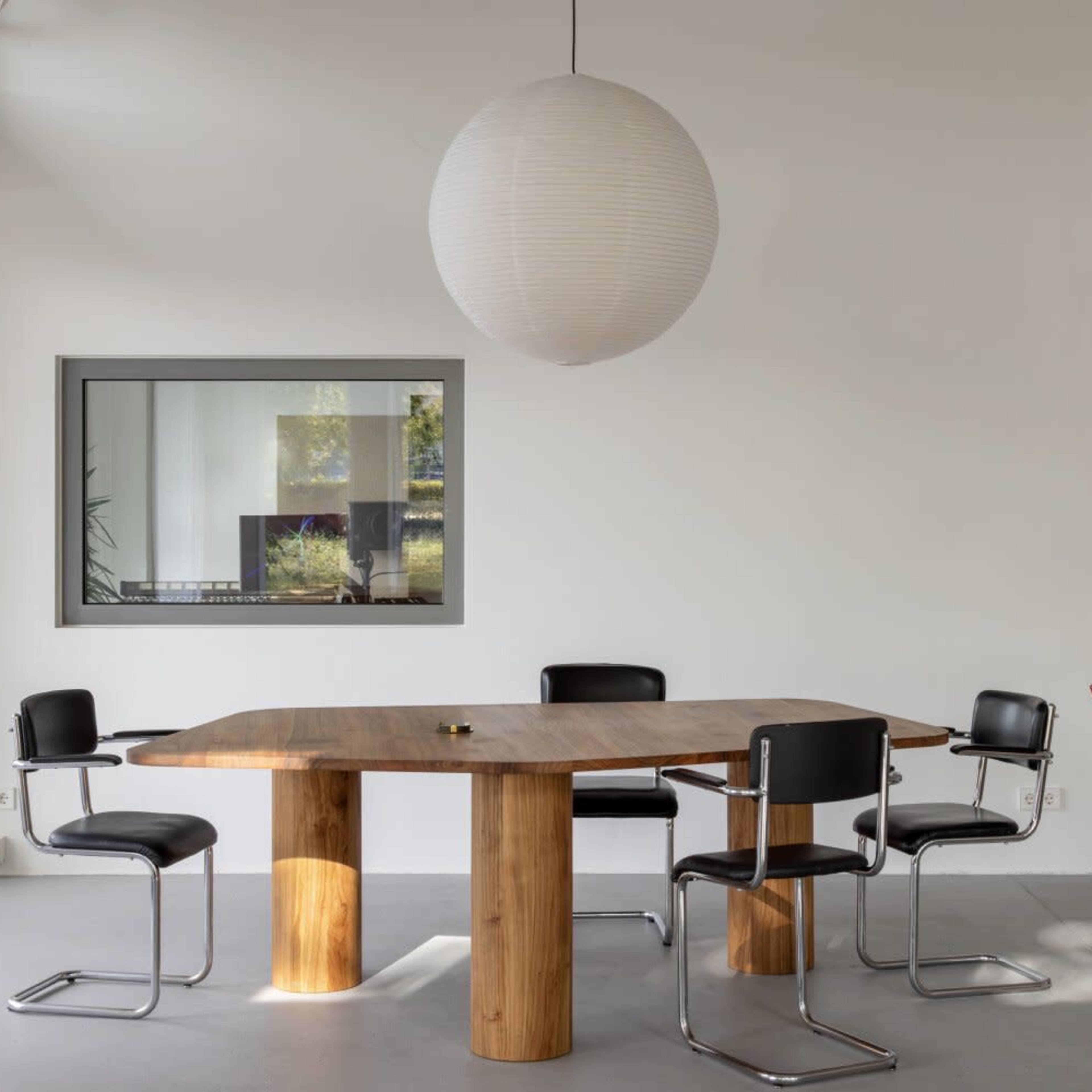 A modern dining area features a wooden table with four black chairs under a round pendant light.