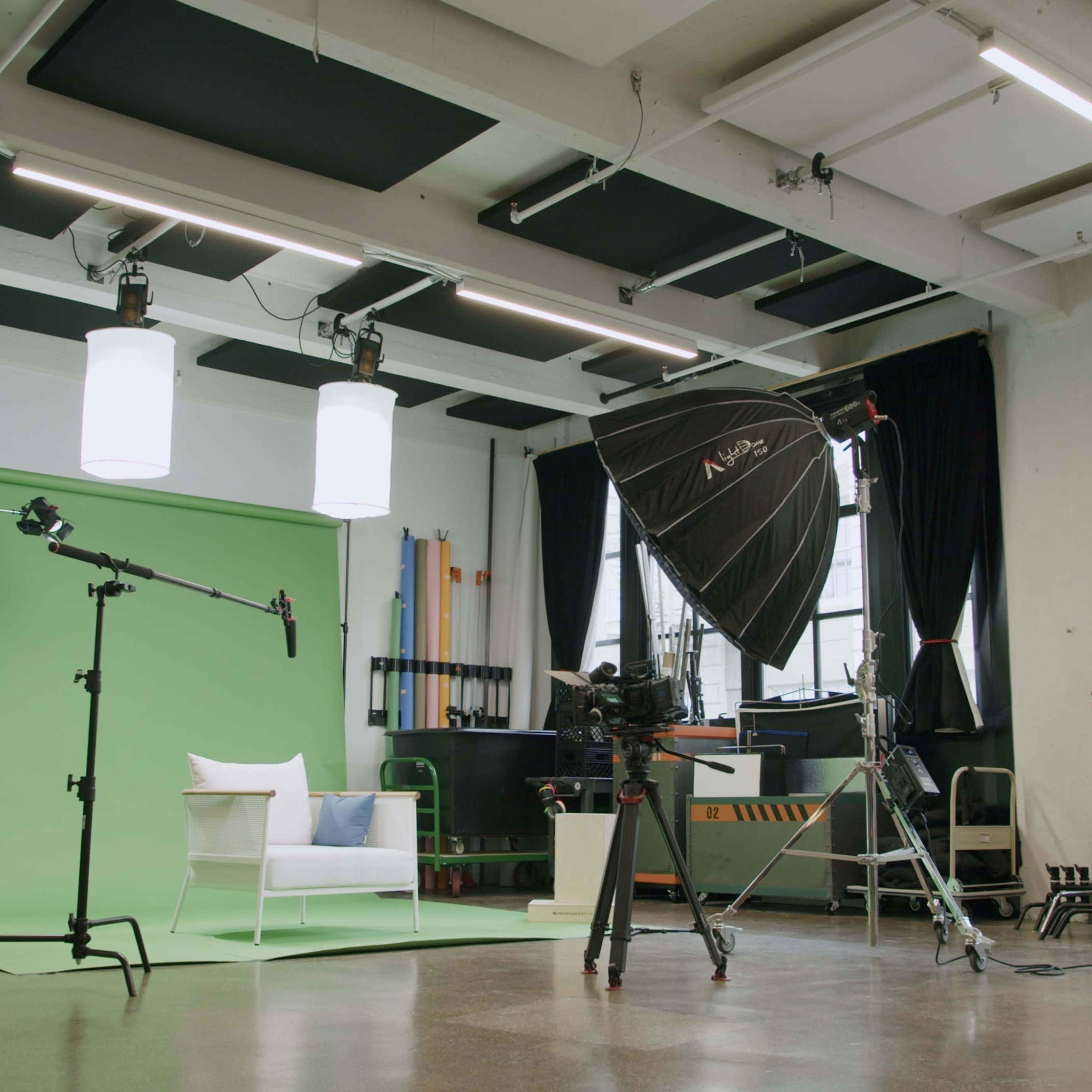 A well-lit studio setup featuring a green screen, photography equipment, and various props arranged for a shoot.