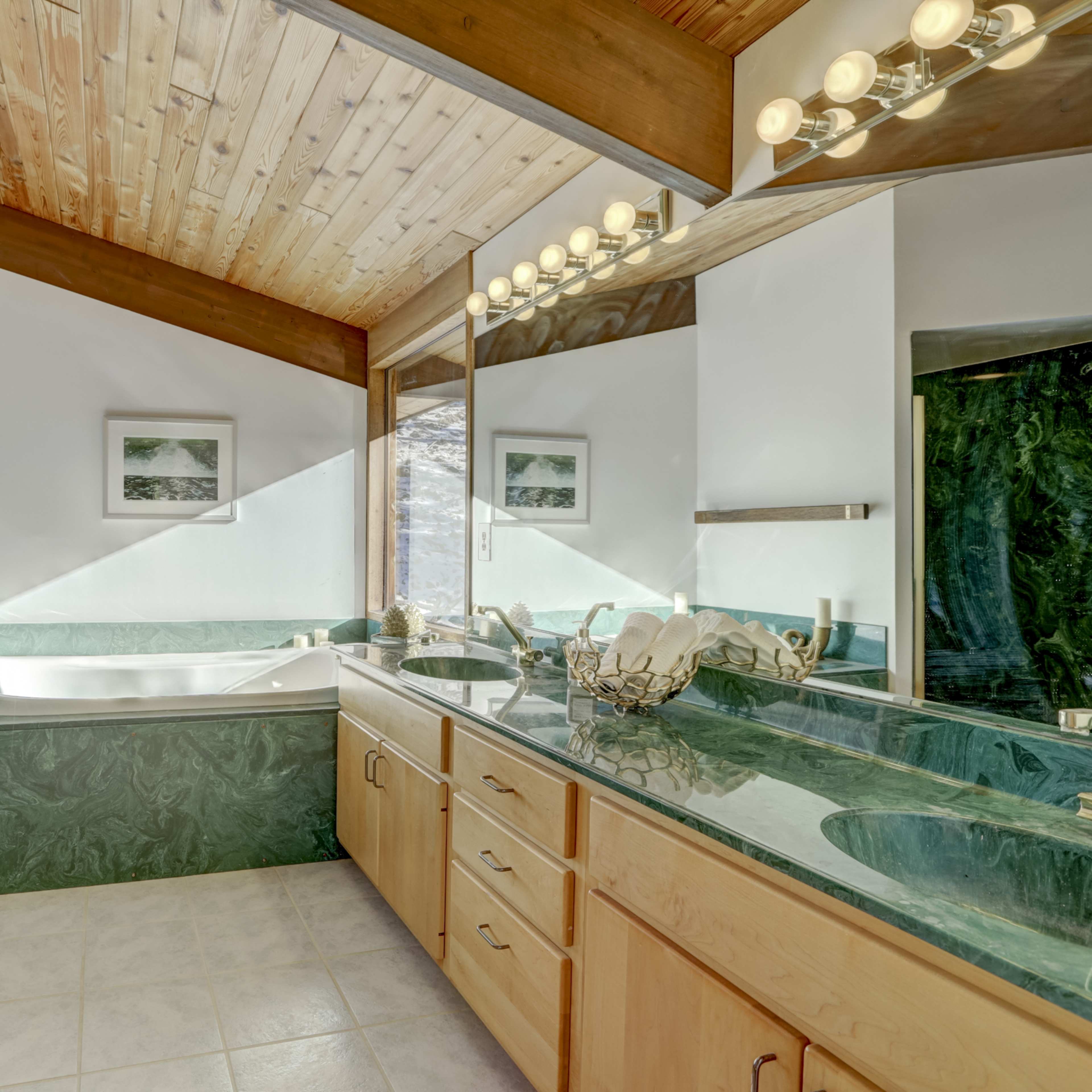 The bathroom features green marble accents, a large soaking tub, a double vanity with wooden cabinets, and a walk-in shower.