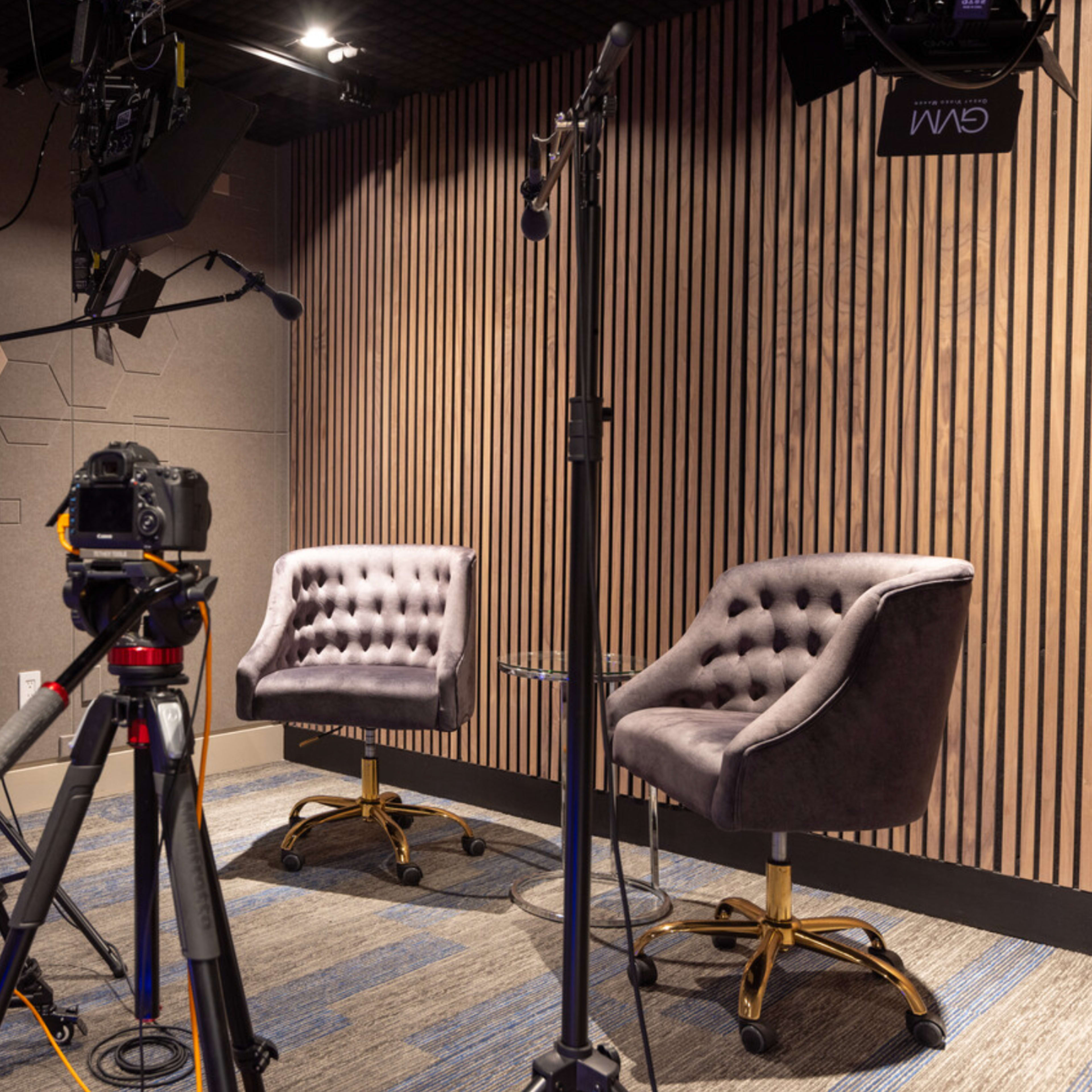 A set designed for video recording, featuring two upholstered chairs and two cameras positioned on tripods.