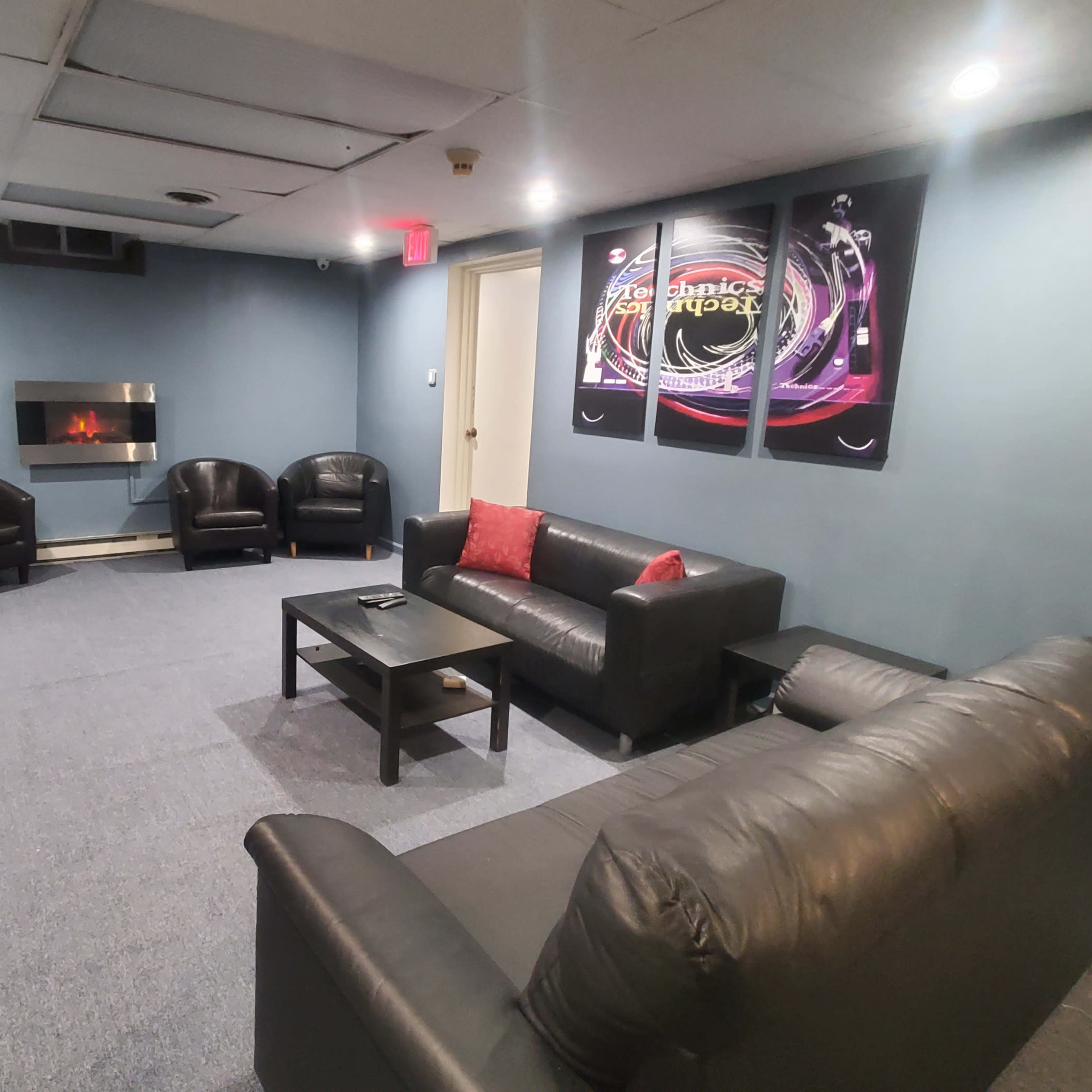 A lounge area with a sofa, chairs, a coffee table, and a wall-mounted television.