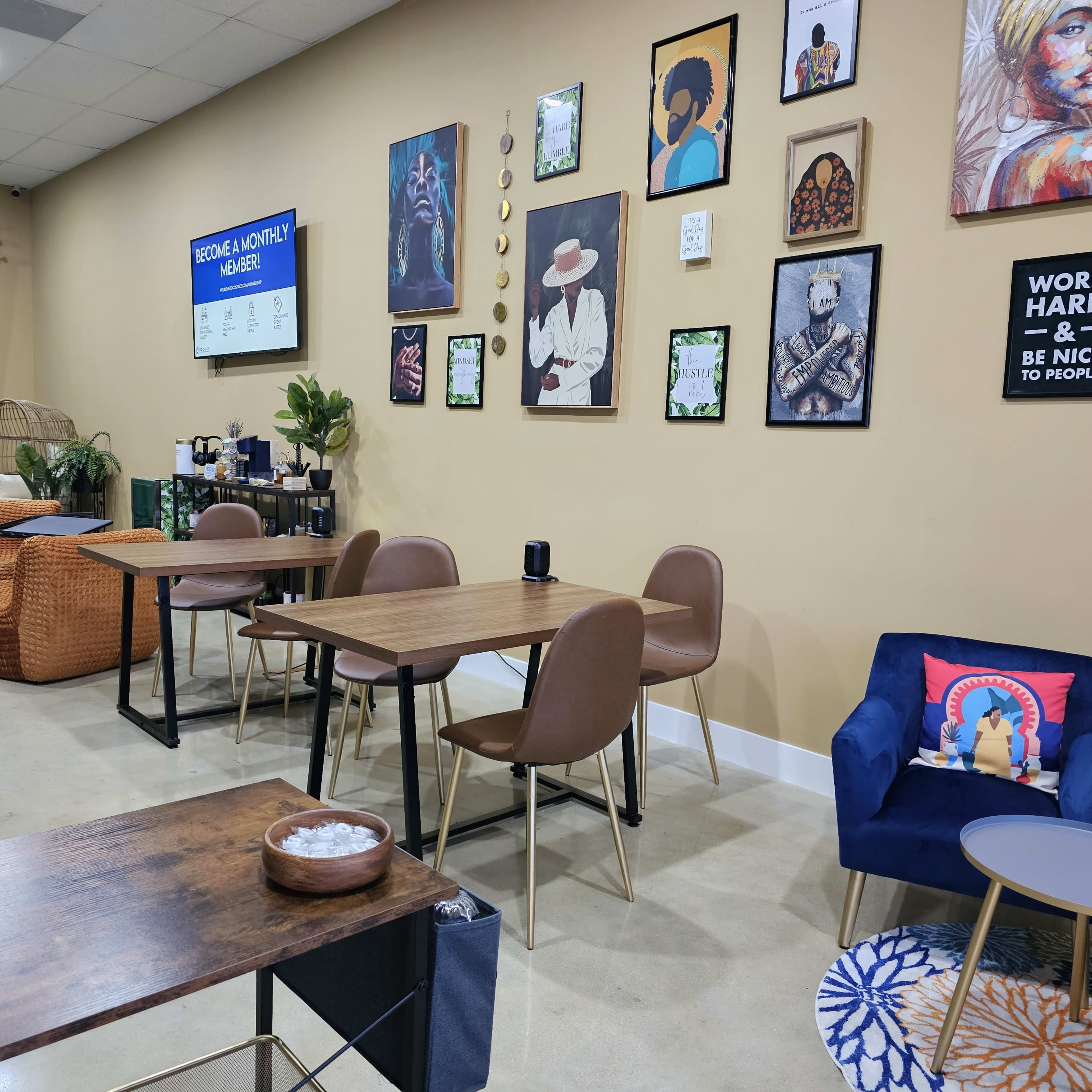 A cozy café interior with wooden tables, brown chairs, and wall art, featuring a green curtain and a small seating area with colorful cushions.