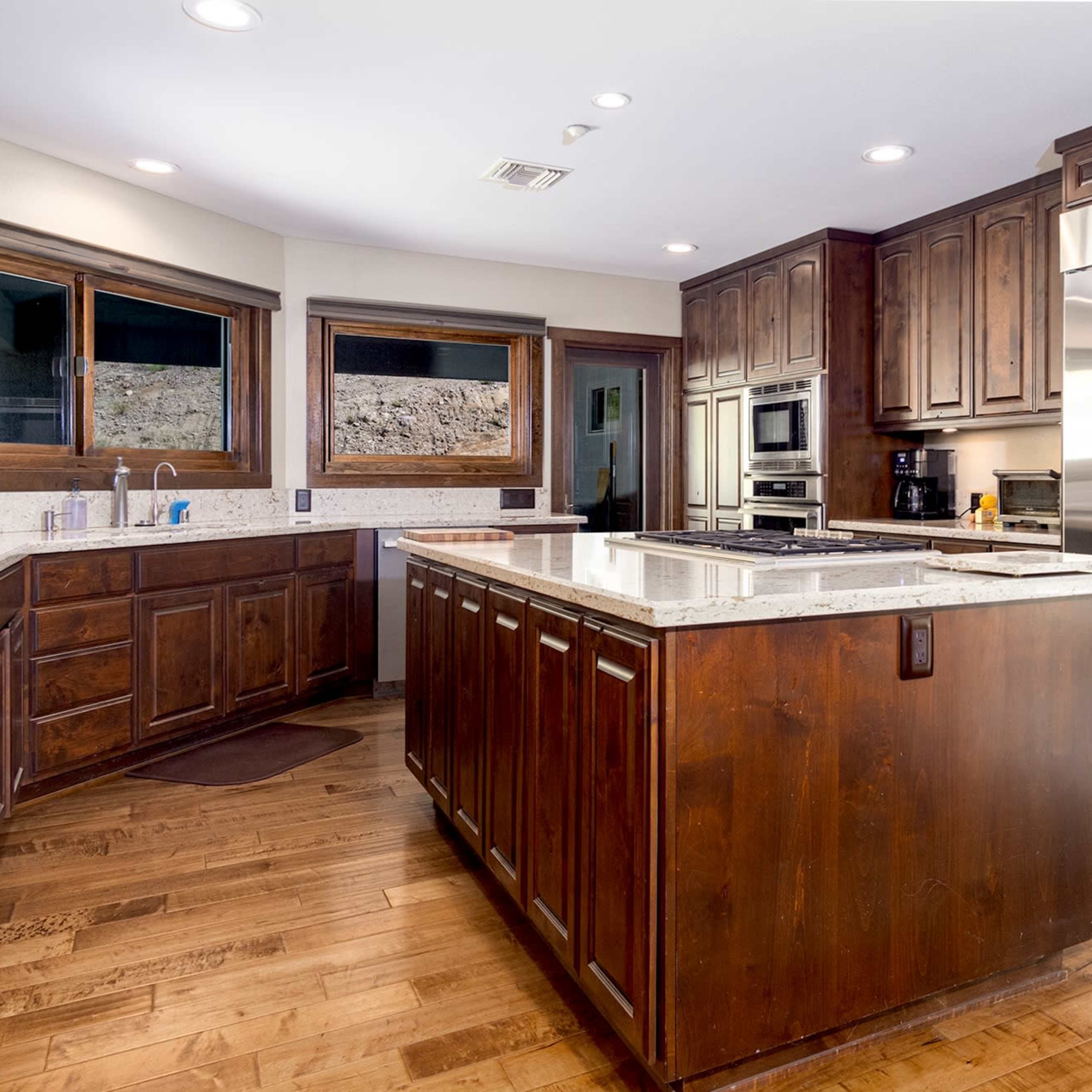 The kitchen features dark wood cabinetry, a central island with a granite countertop, and stainless steel appliances.
