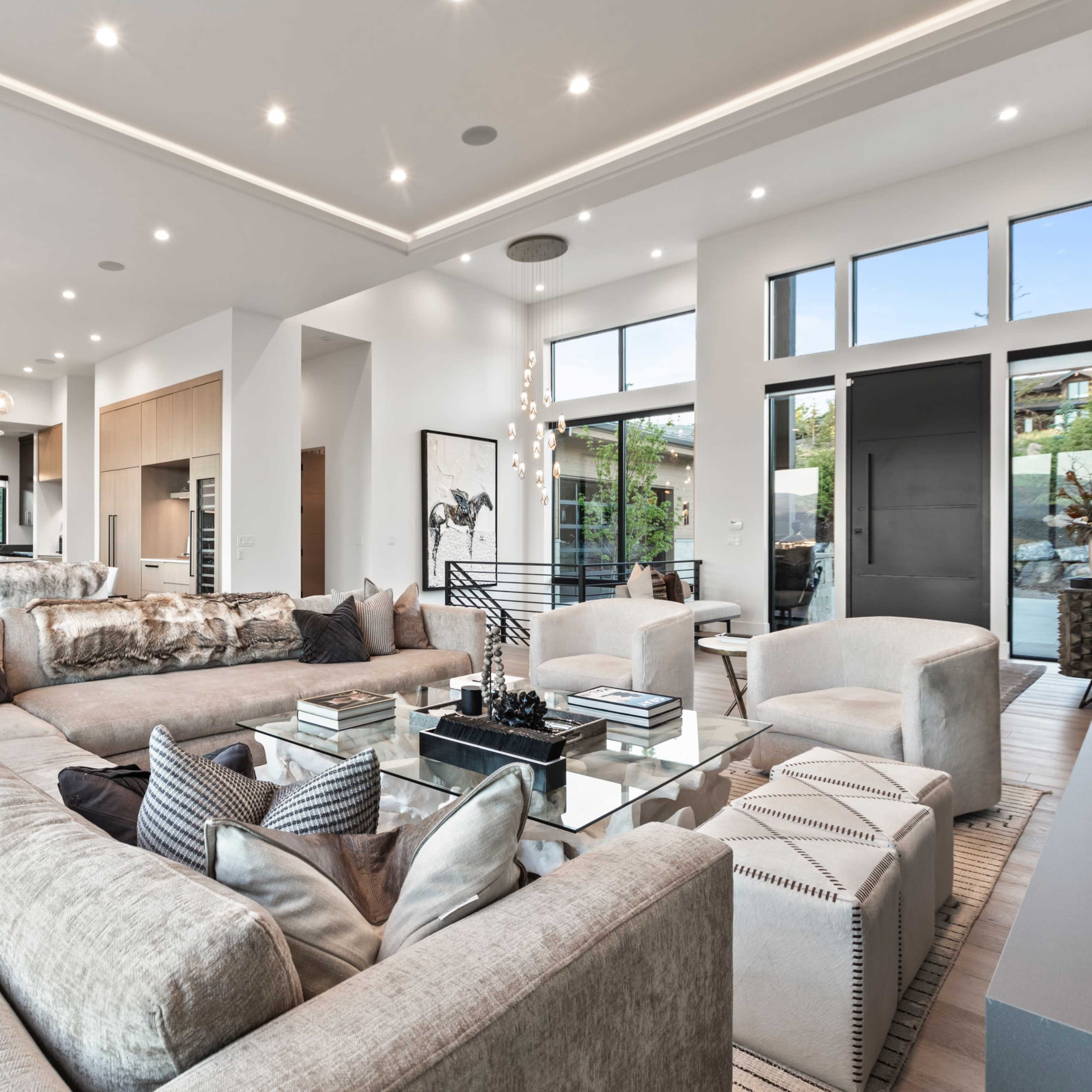 A modern, open-concept living area featuring a spacious sectional sofa, simple decorative elements, and large windows that provide natural light.
