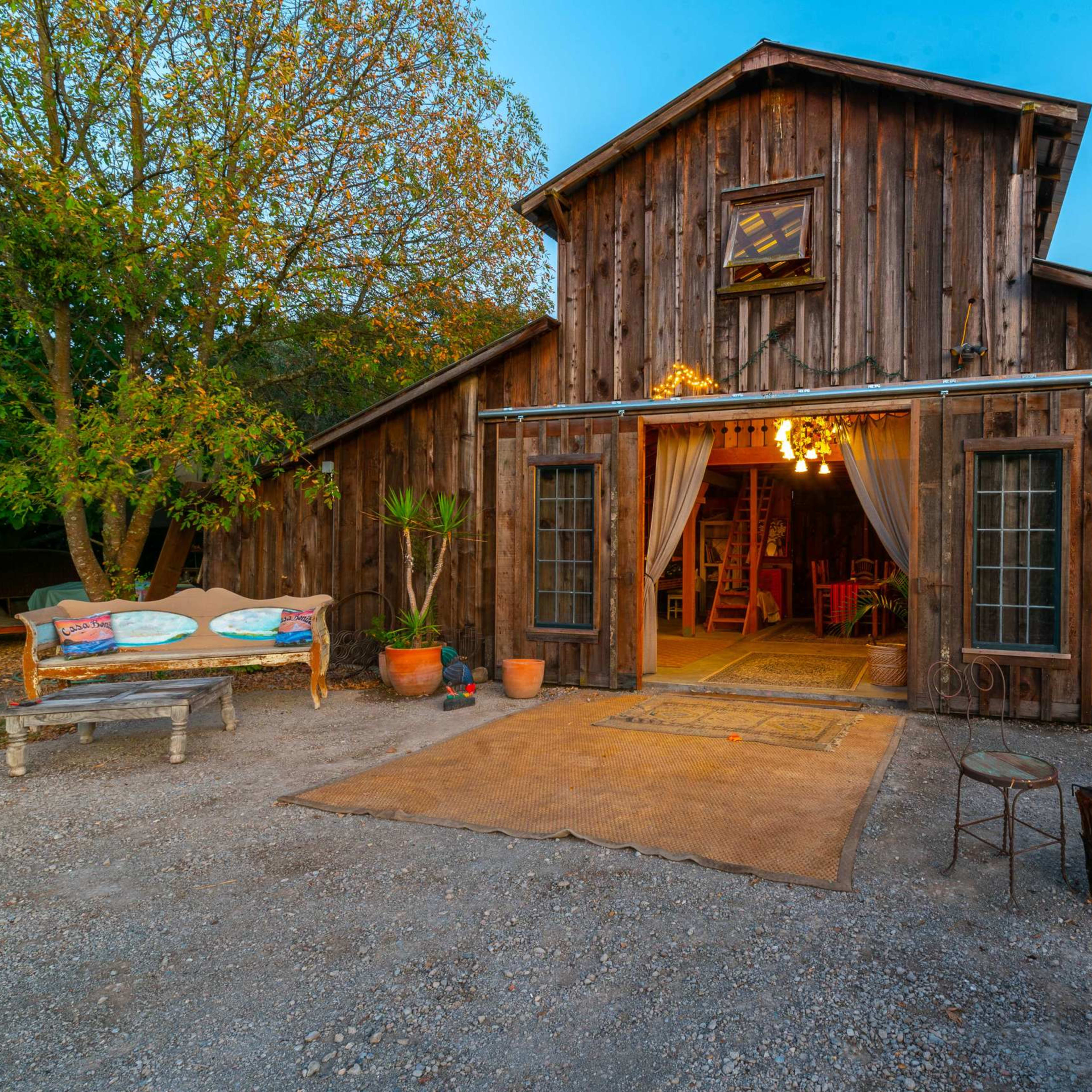 A rustic wooden building with an inviting entrance, surrounded by trees and outdoor seating areas.