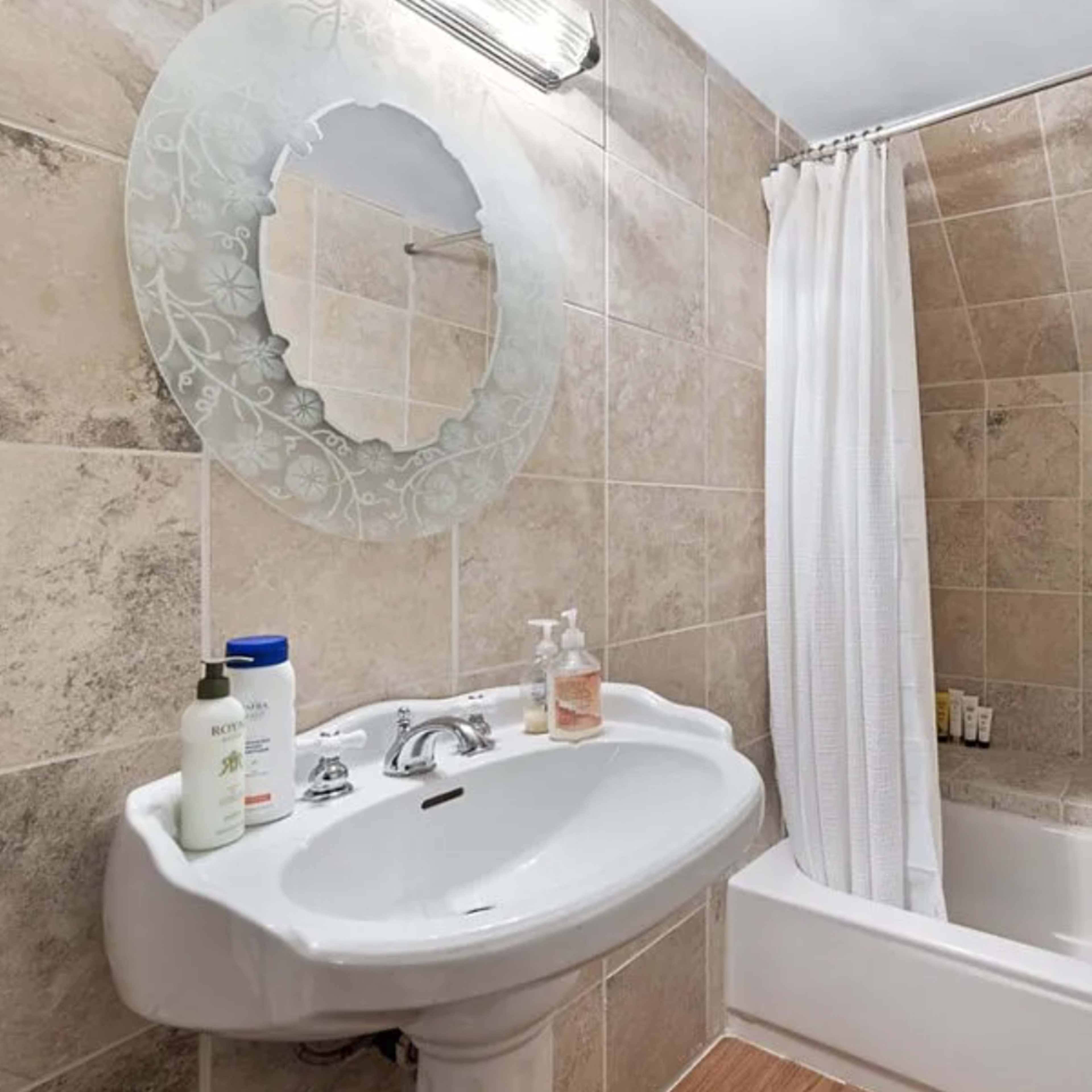 A bathroom featuring a sink, a bathtub with an attached shower curtain, and tiled walls.