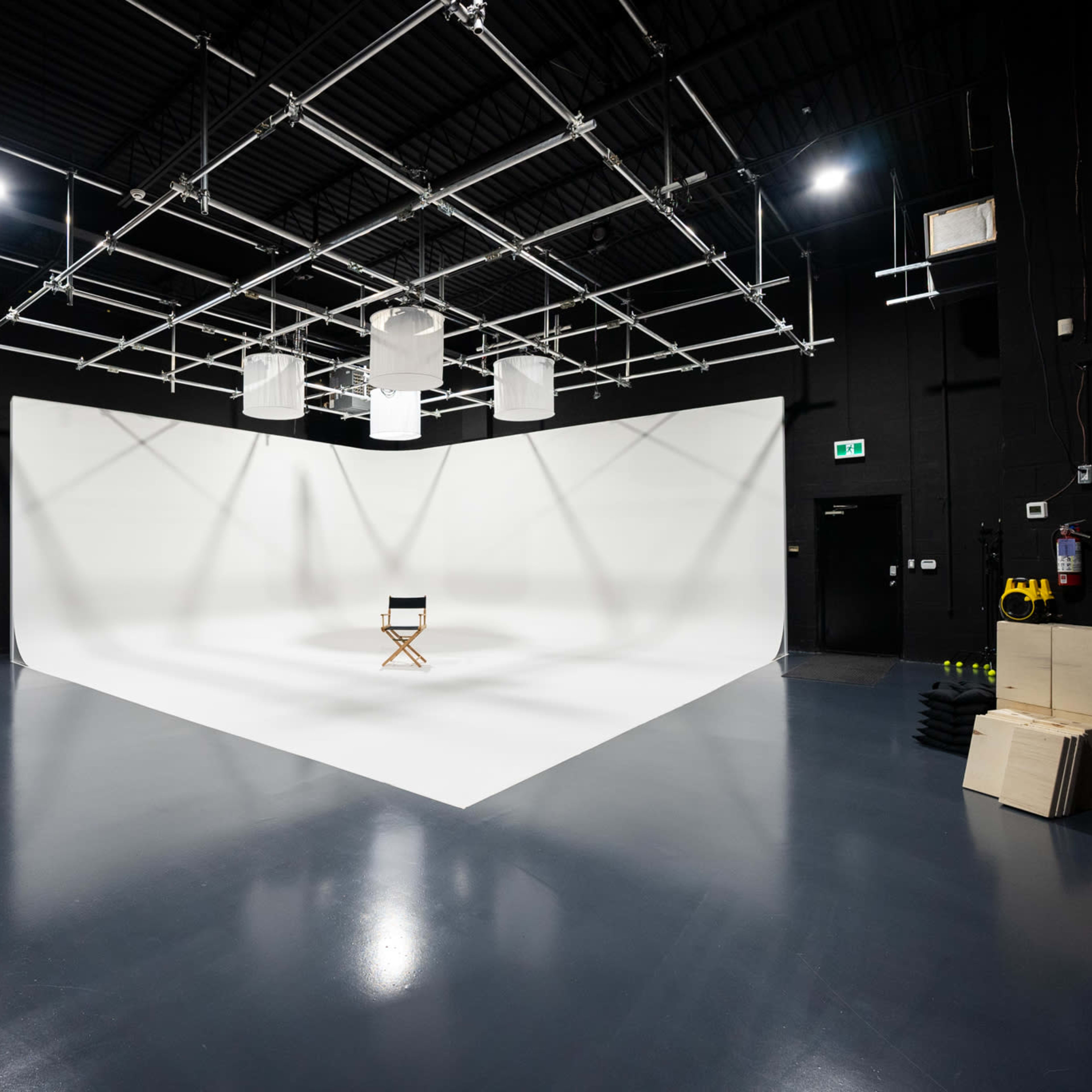 A film studio features a white backdrop with a single director's chair placed in the center.