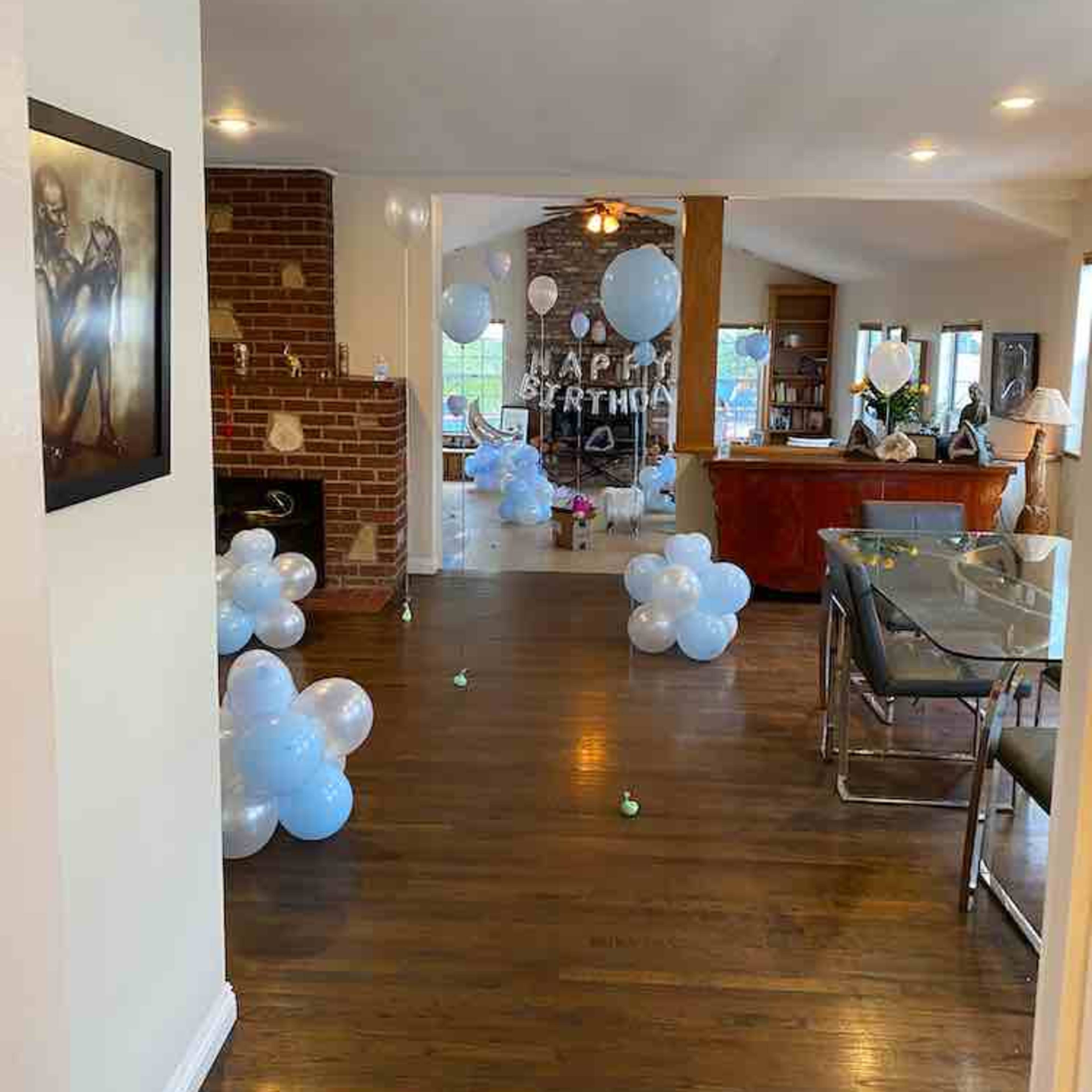 A spacious living area decorated with balloons and a table set for a birthday celebration.