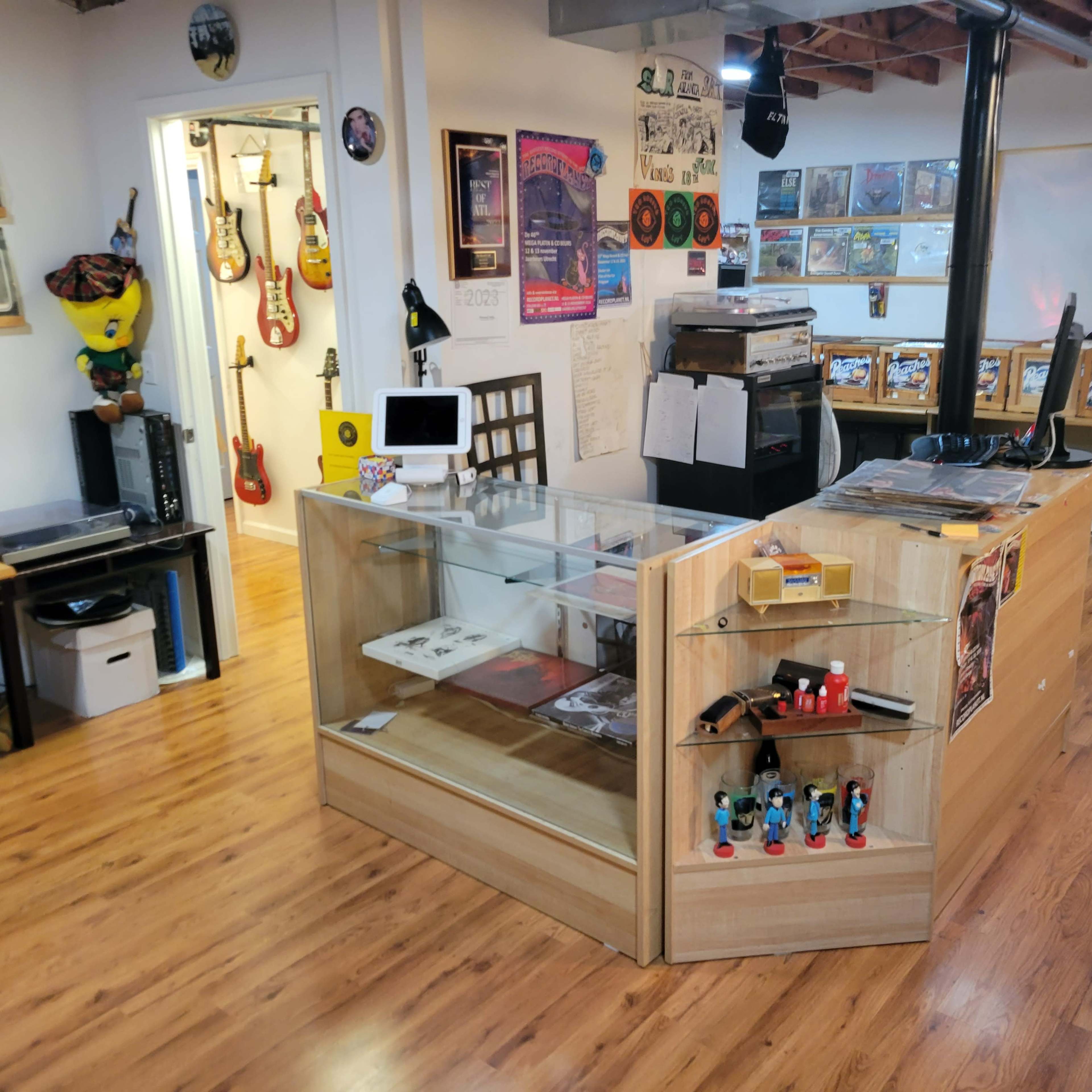 A music-themed store interior with display cases, instruments on the walls, and a counter for transactions.