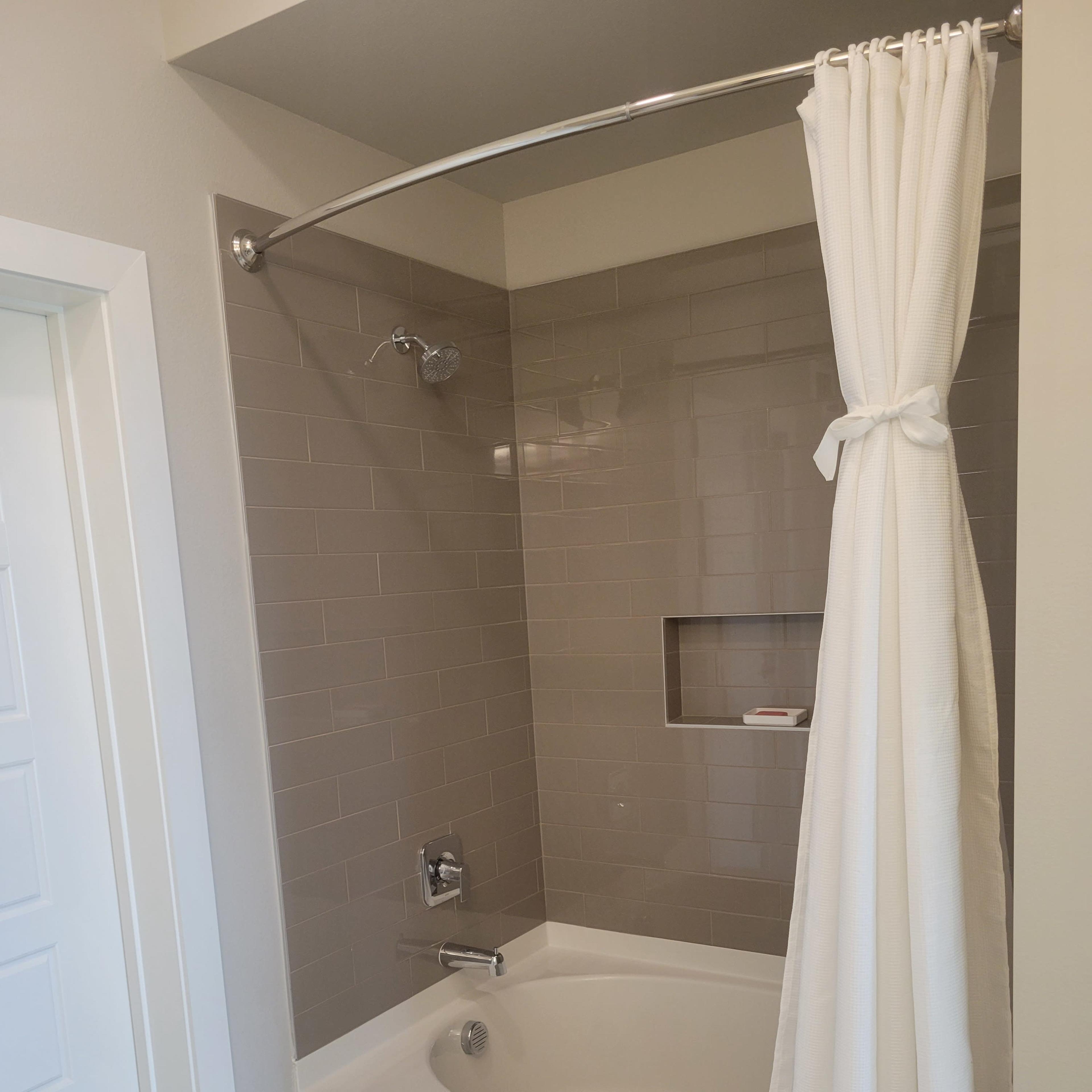 A bathroom with a bathtub, a shower curtain, and tiled walls.