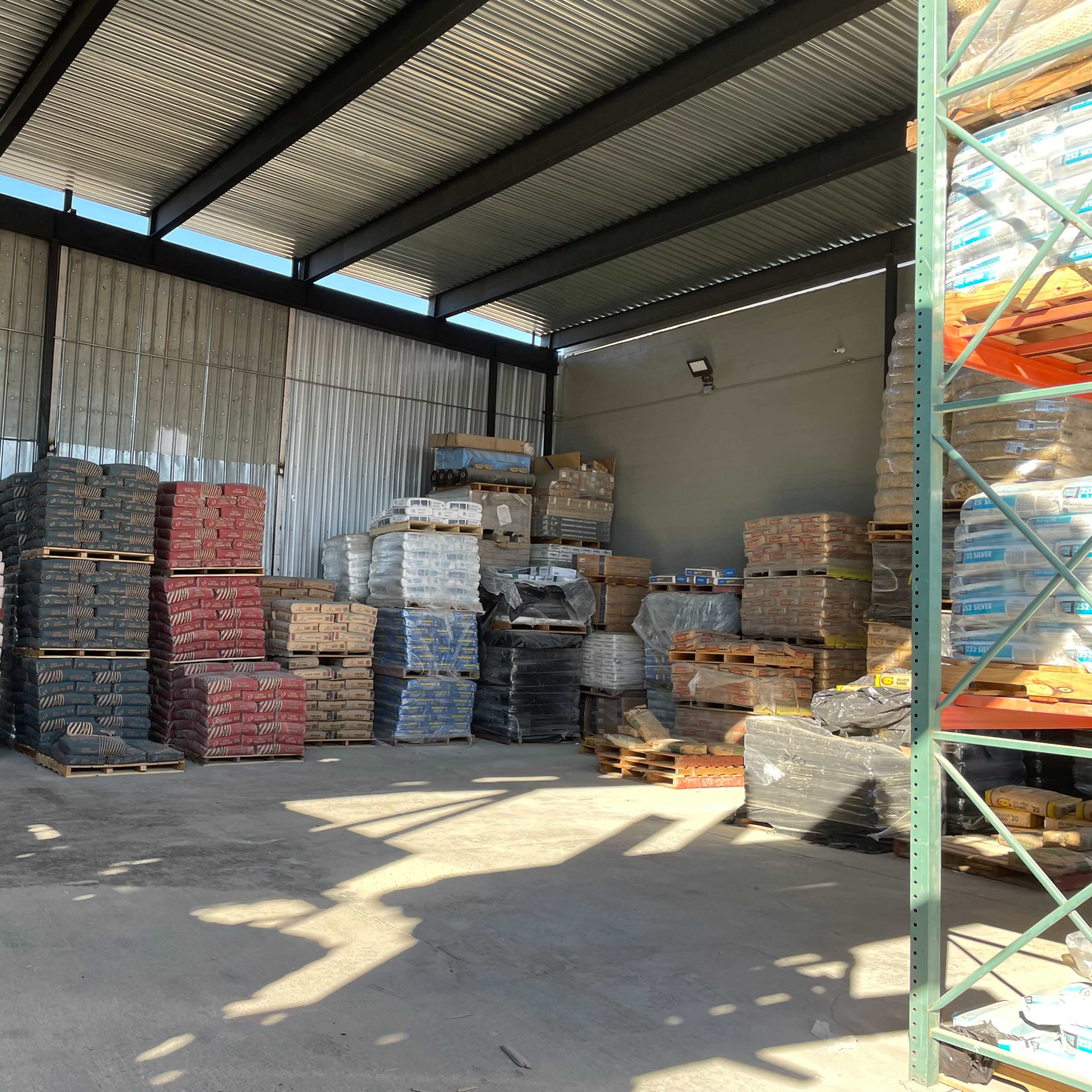 A storage facility with stacked pallets of various materials arranged against the walls.