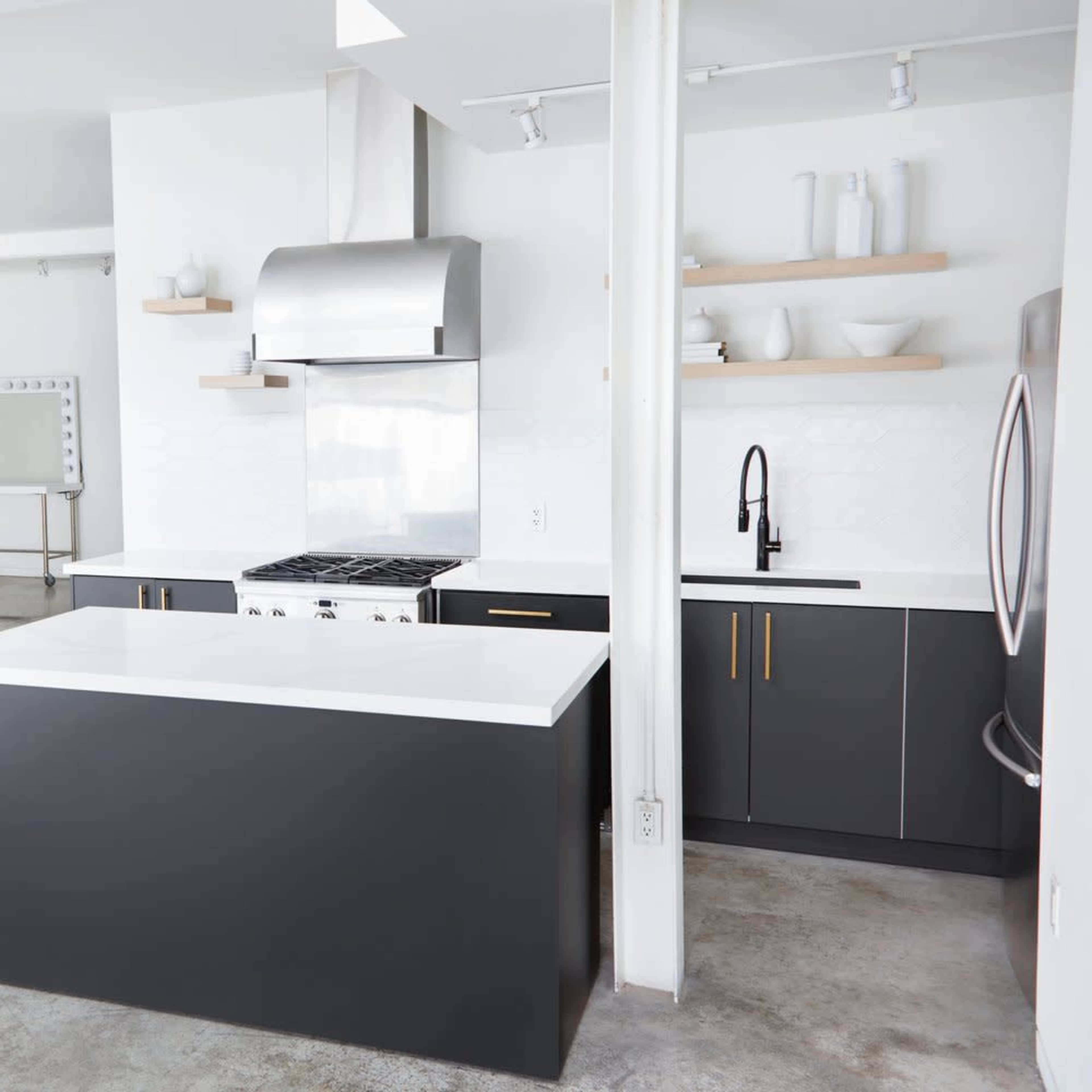 A modern kitchen with a central island, stainless steel appliances, and a dining area with a wooden table and metal chairs.