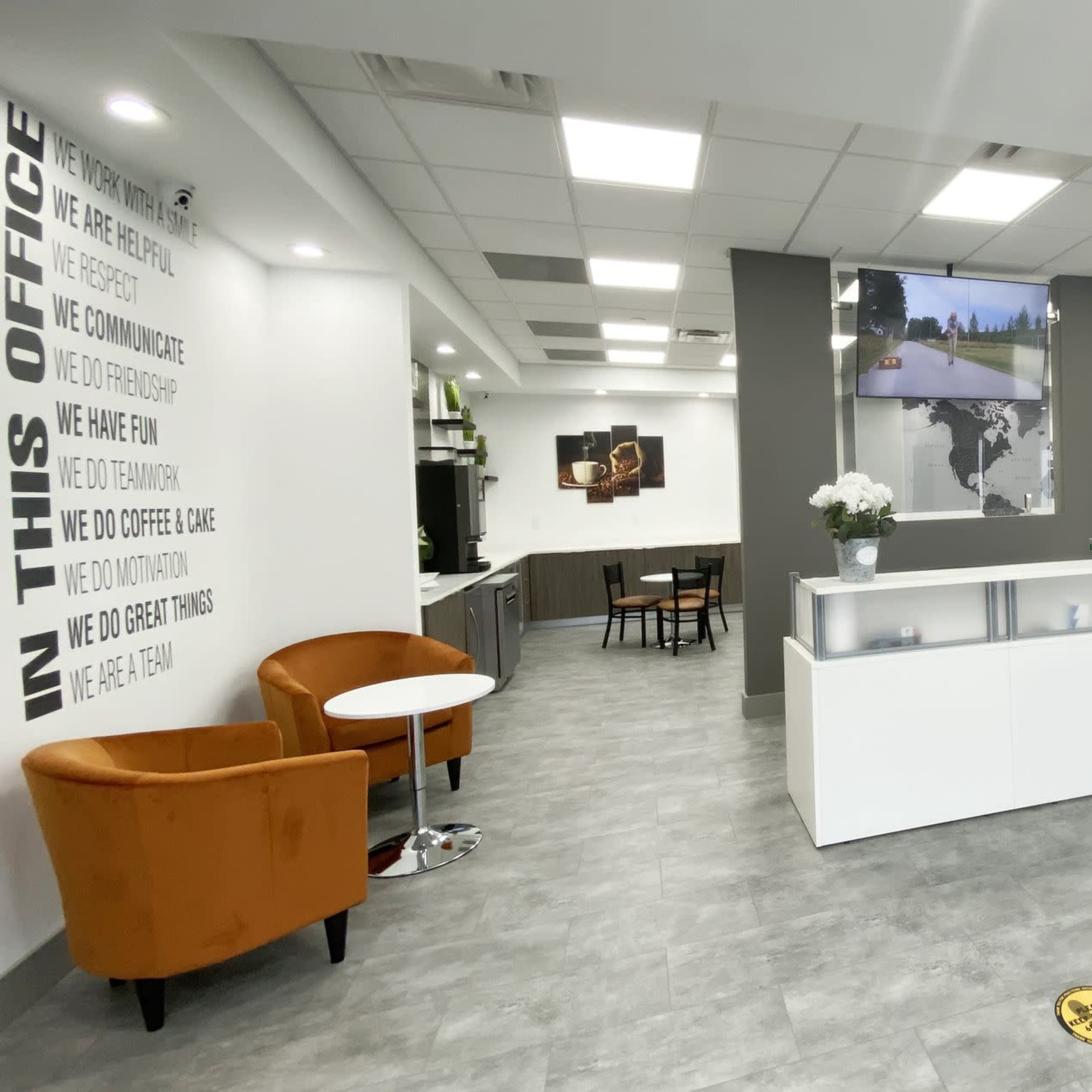 A modern office reception area with a clean layout, featuring a front desk, seating arrangements, and motivational phrases on the walls.