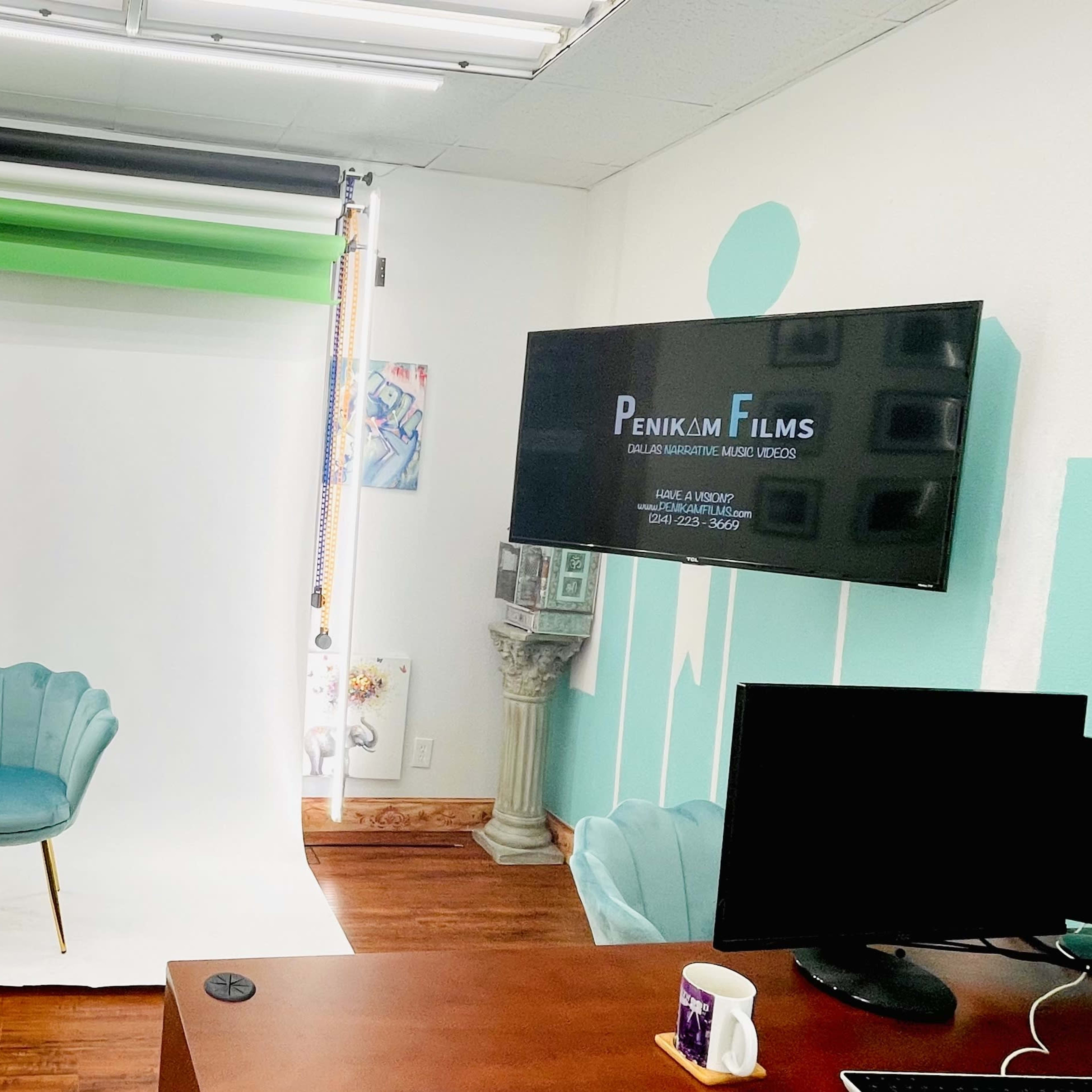 A photography studio setup featuring a green screen backdrop, a white backdrop, a teal chair, and a television displaying a logo for "Penlink Films."
