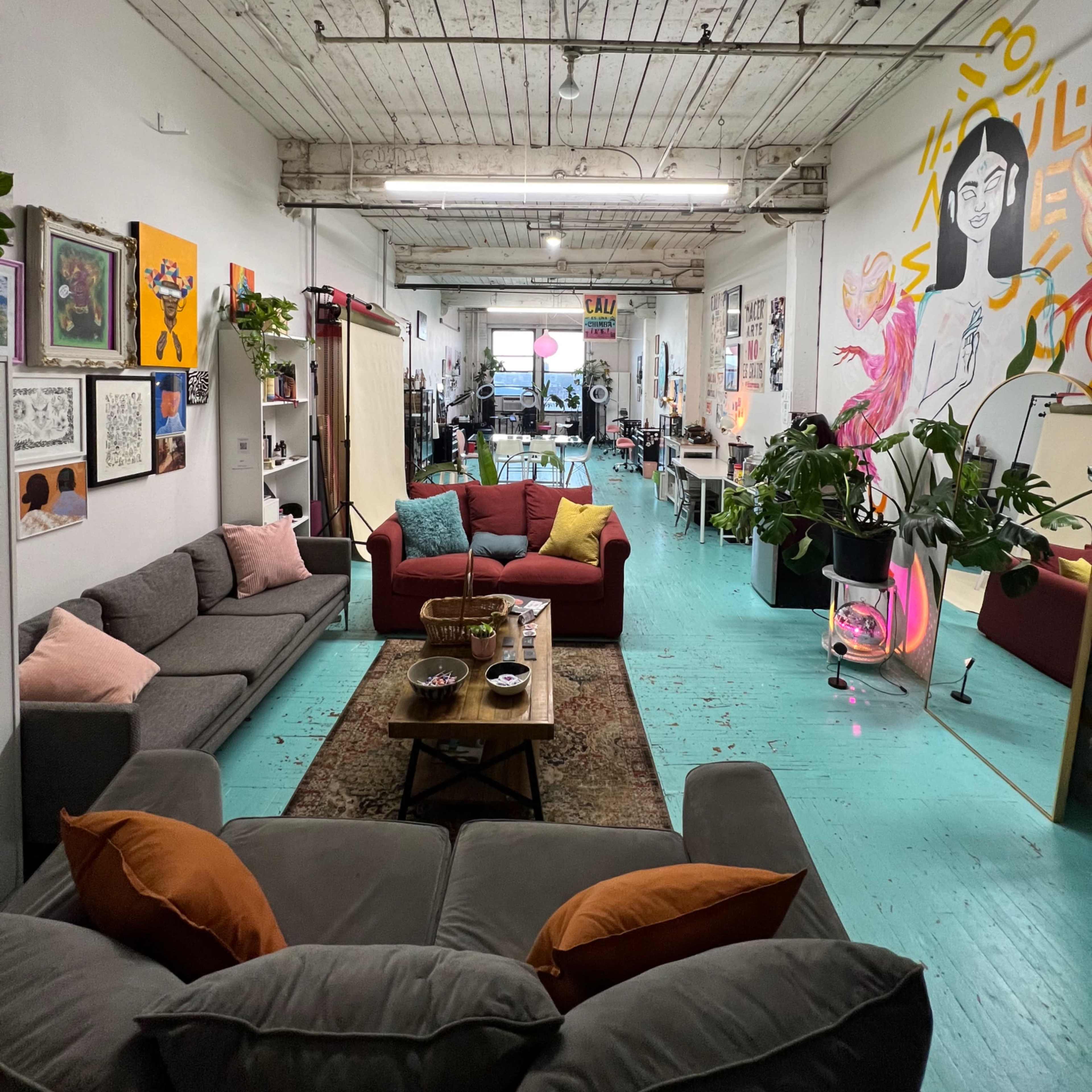 A spacious, brightly lit room with modern furniture, including two sofas, a coffee table, and vibrant wall art.