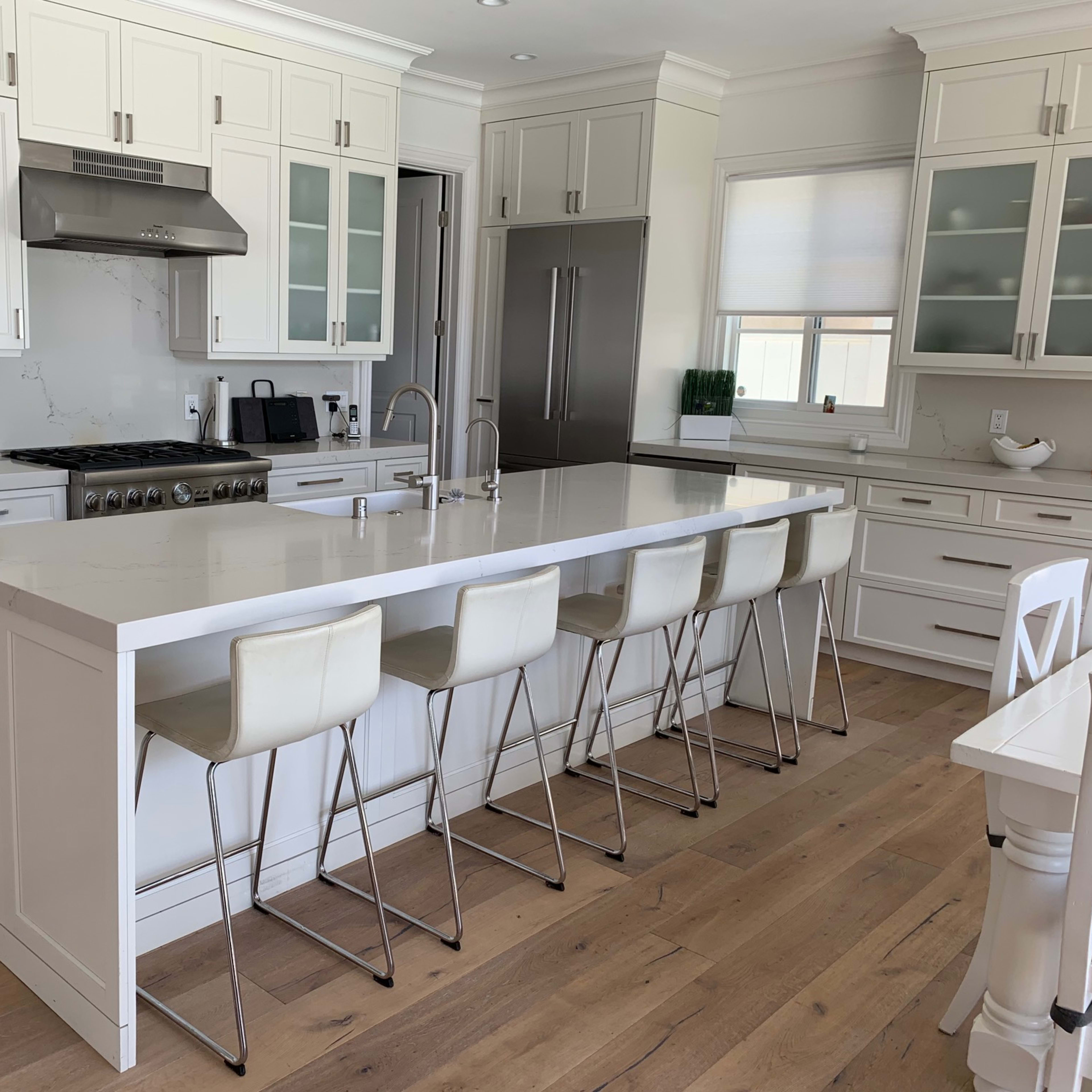 A modern kitchen with white cabinetry, a large island with seating, and stainless steel appliances.