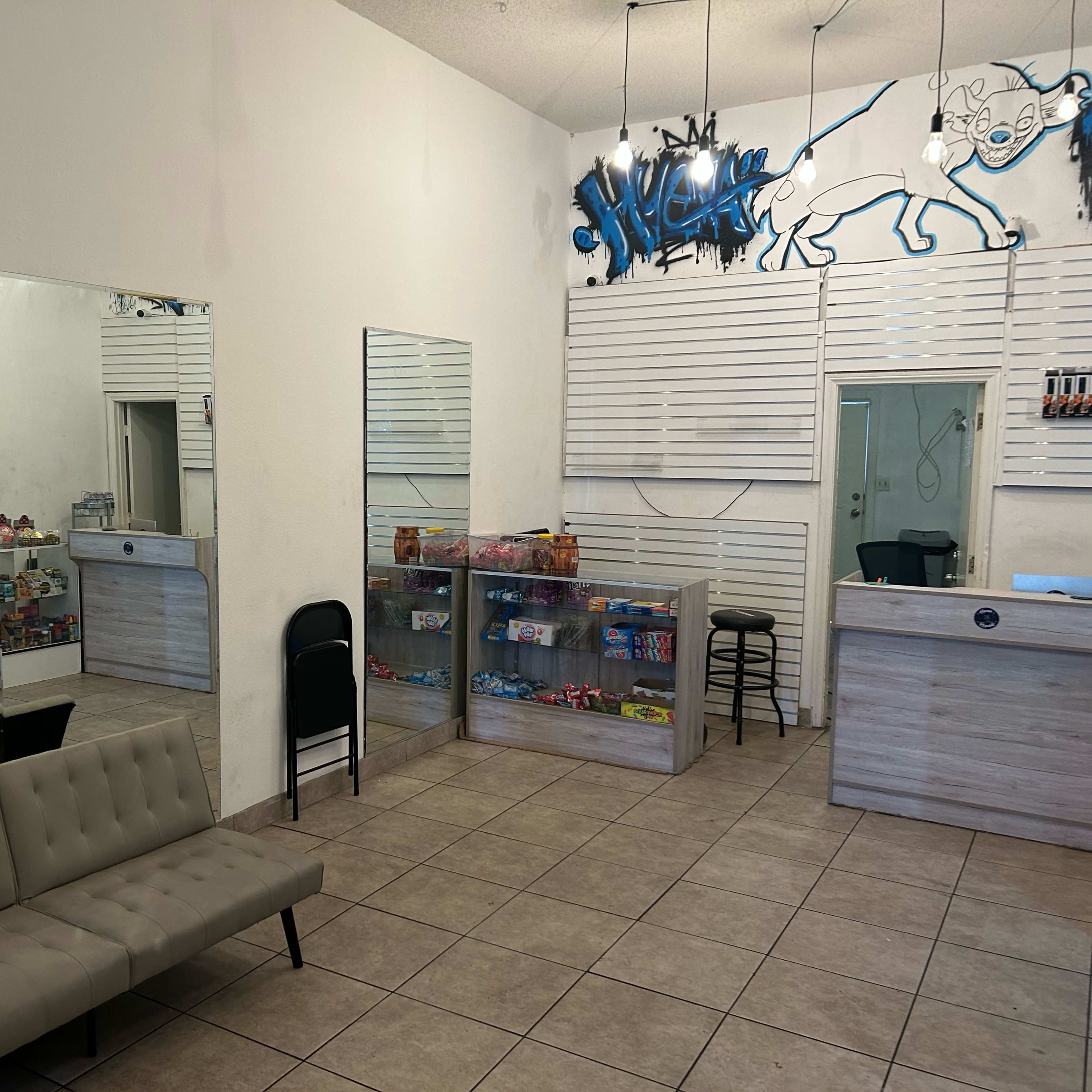 A small storefront interior with a seating area, display shelves filled with snacks, and a counter at the back.