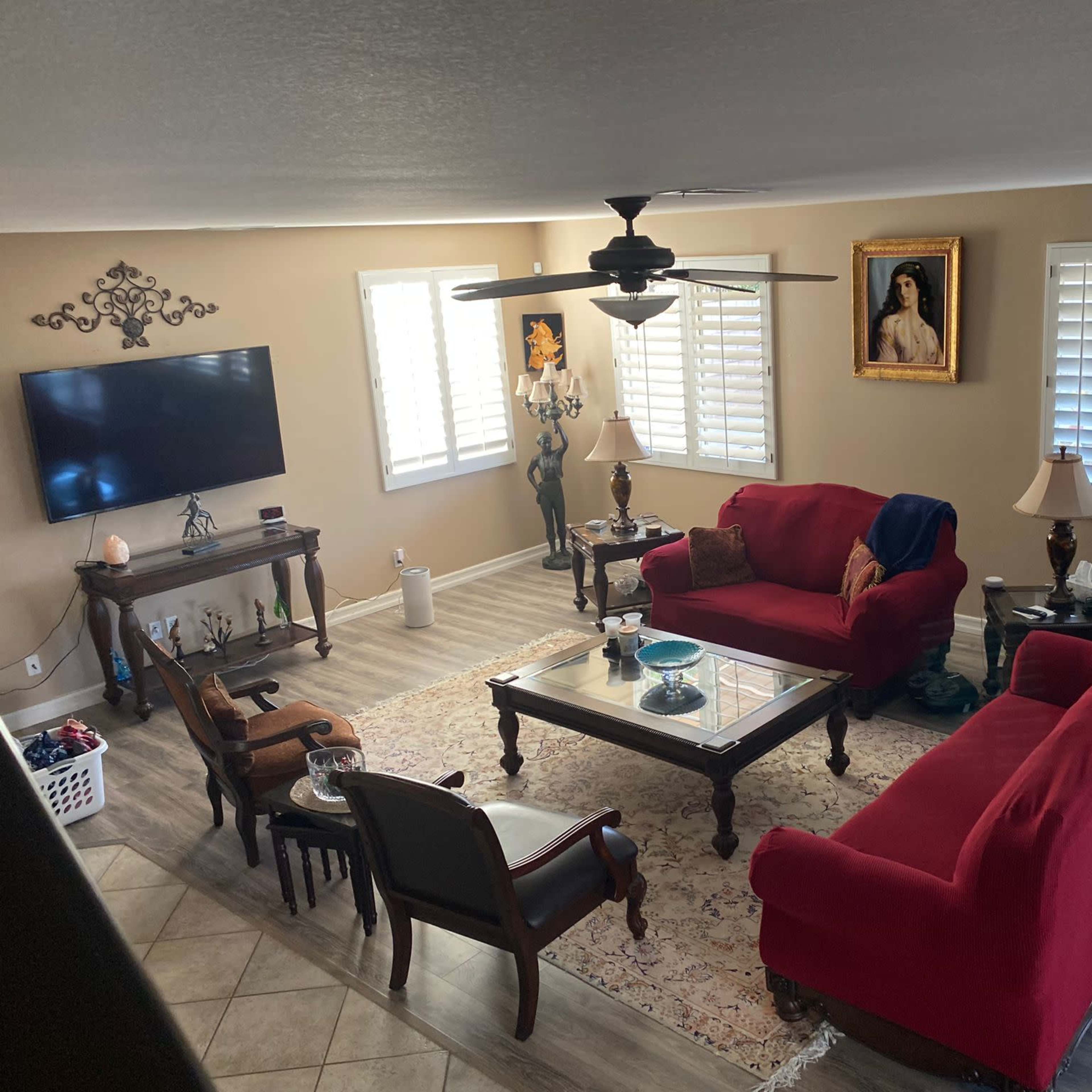 A living room with red sofas, a coffee table, a large TV, and framed artwork on the walls, along with a decorative rug and various furnishings.