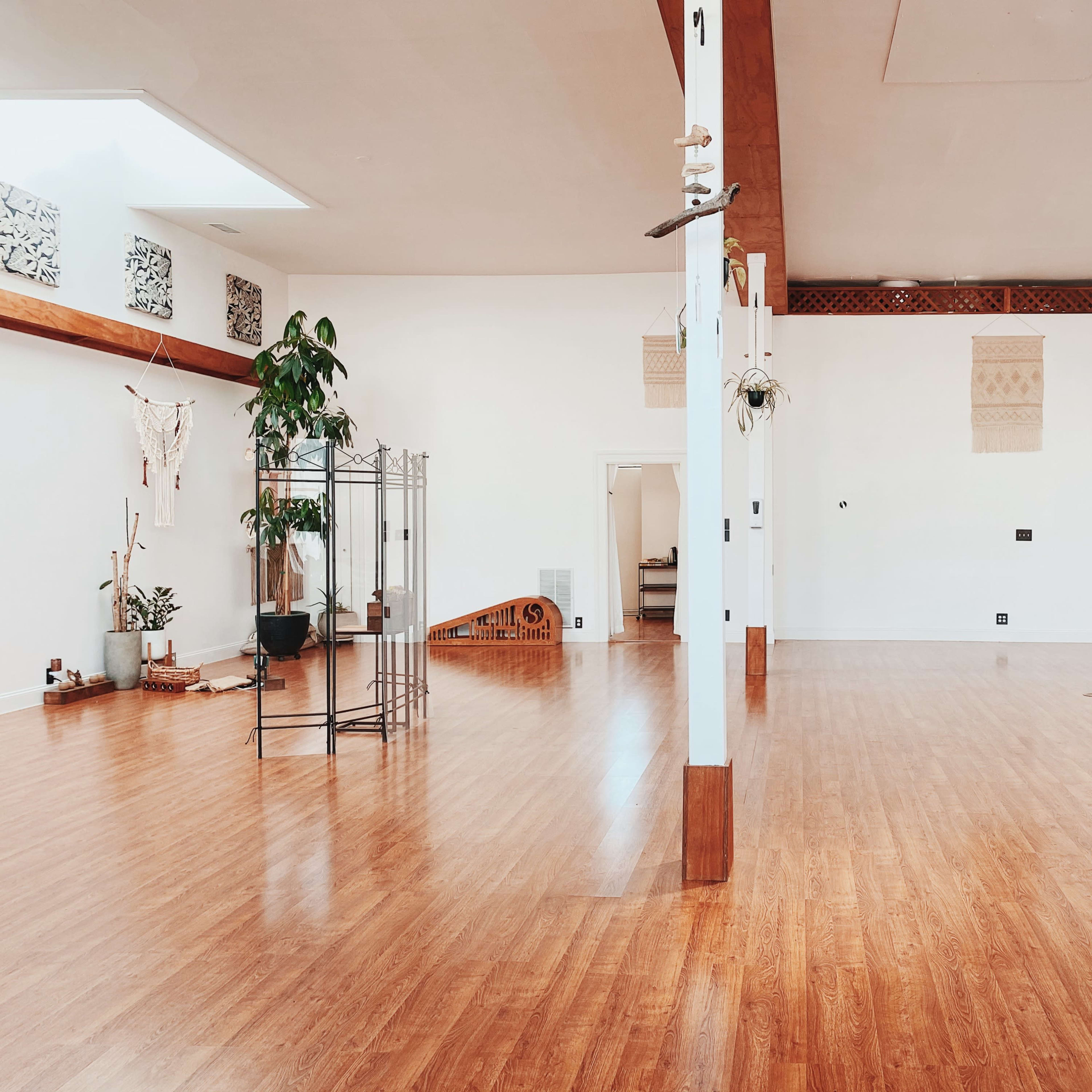 A spacious, empty room with wooden flooring, large skylights, and decorative elements along the walls.