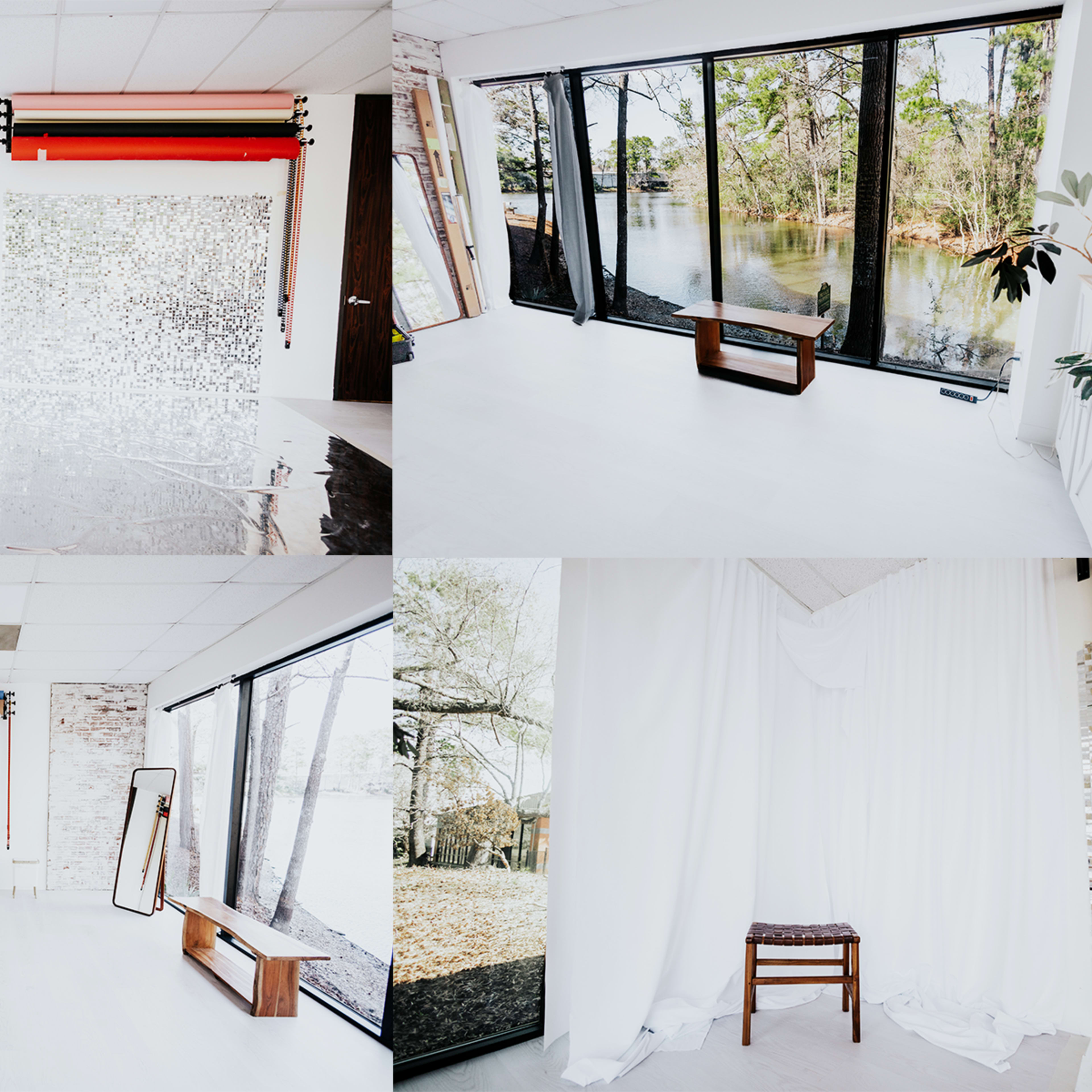 A bright, minimalist interior space featuring large windows with a view of water, a small wooden chair, and various backdrops on the walls.