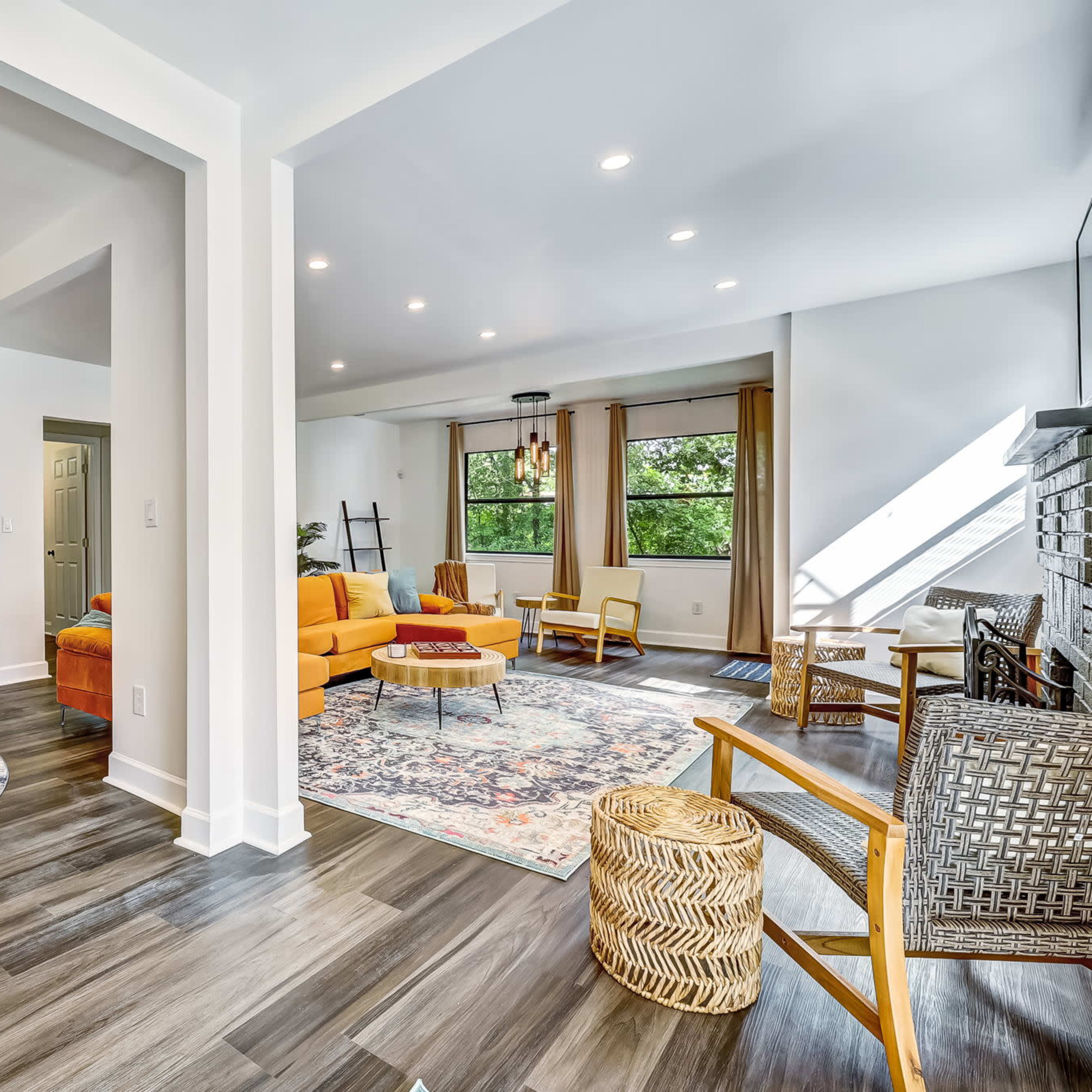 A modern living space featuring a yellow sofa, a dining area with a round table, and a mix of hardwood and area rugs.