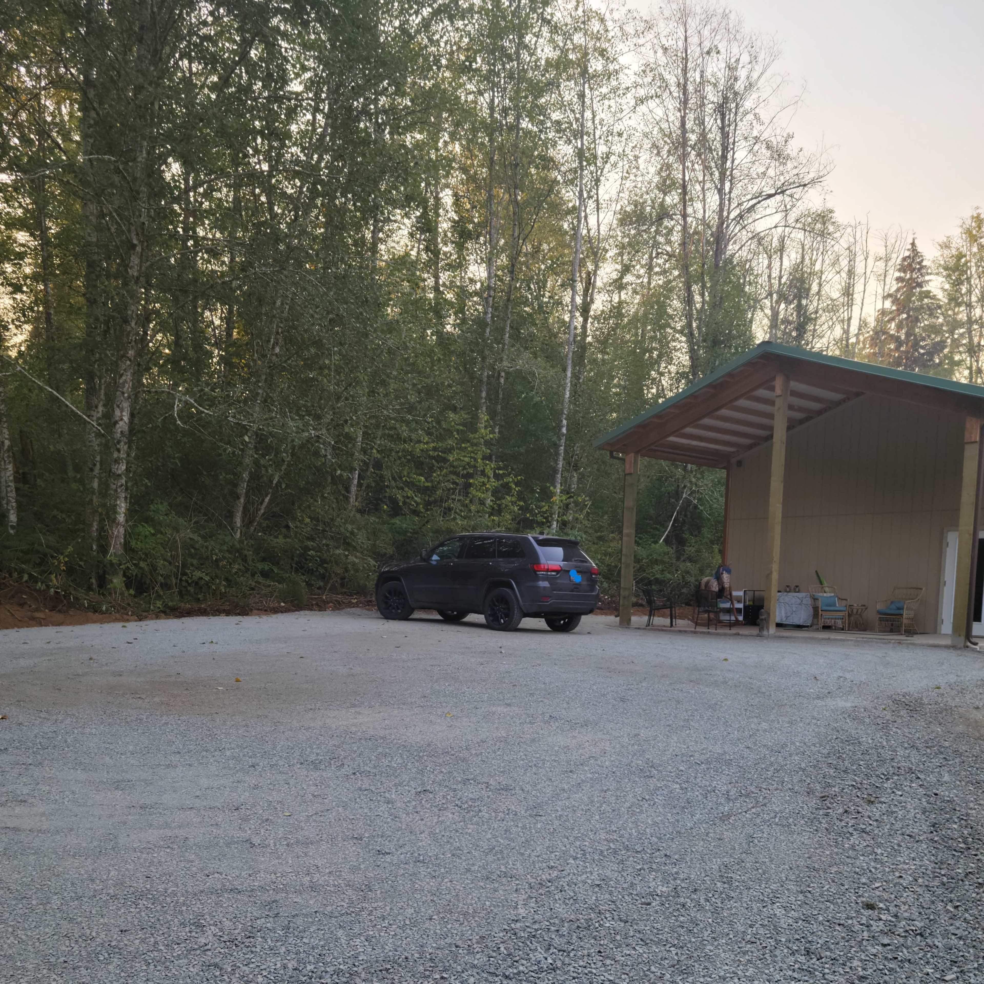 A large gravel area features an SUV parked near a covered structure with a person seated nearby.