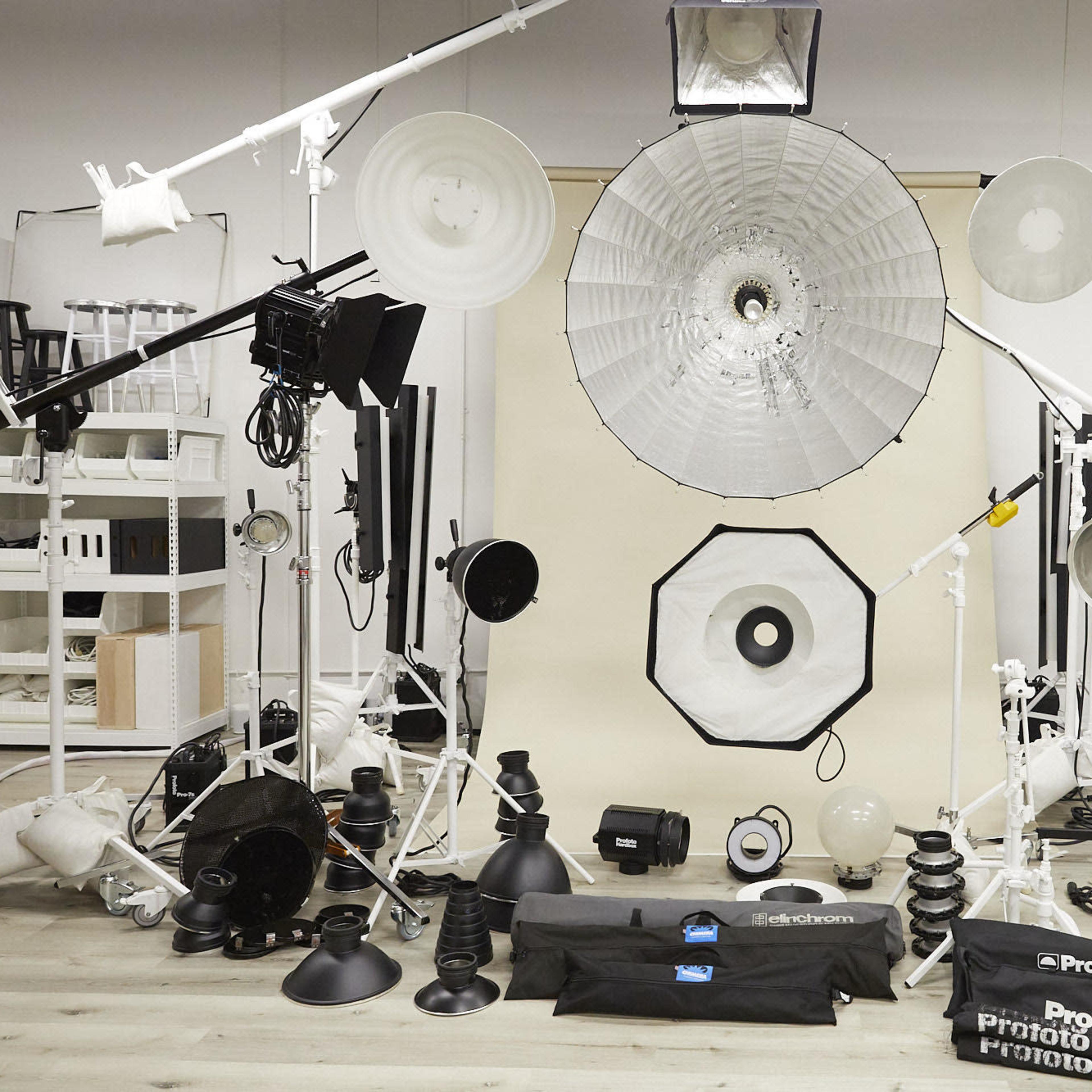 A photography studio setup with various lighting equipment arranged around a central backdrop.